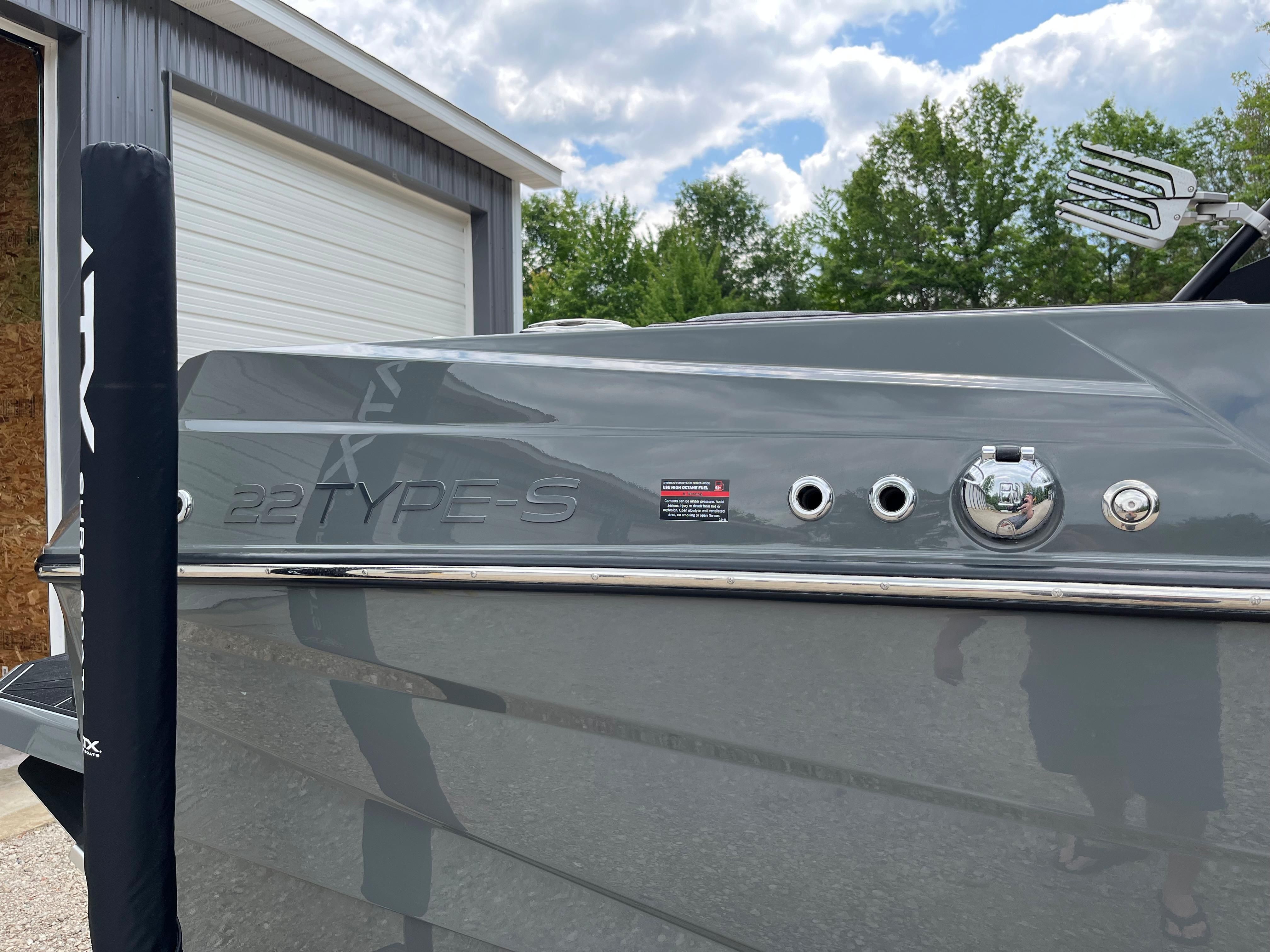 A gray 2022 ATX Surf Boat 22 Type-S is parked in front of a garage.