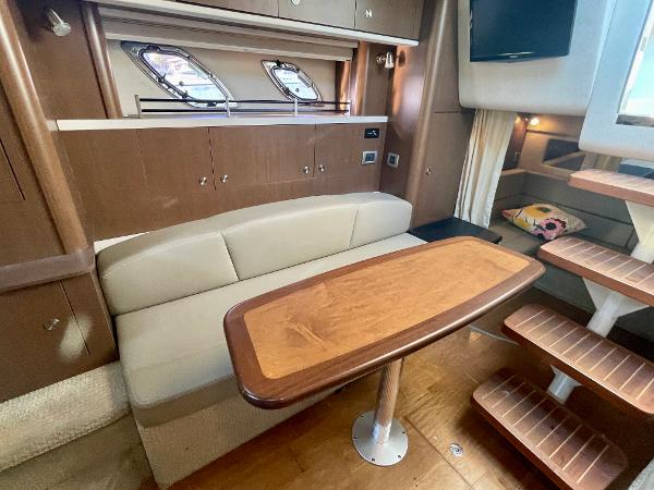 2014 Sea Ray 330 Sundancer interior with wooden table, beige seating, and modern cabinetry.