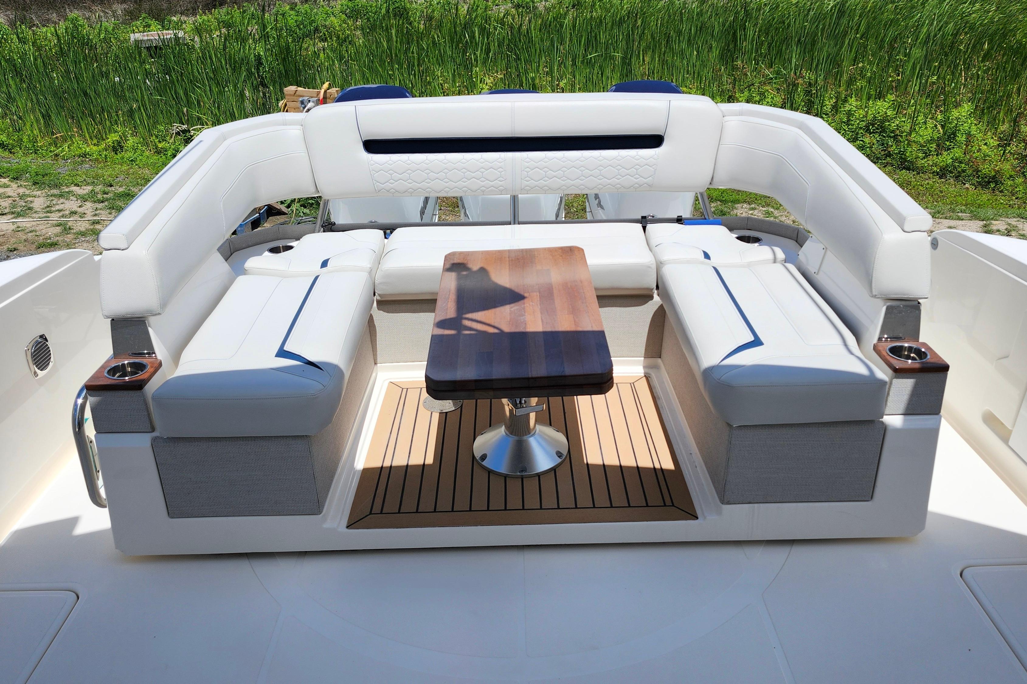 Luxurious seating area on 2022 Tiara Yachts 38 LS with wooden table and white cushions.