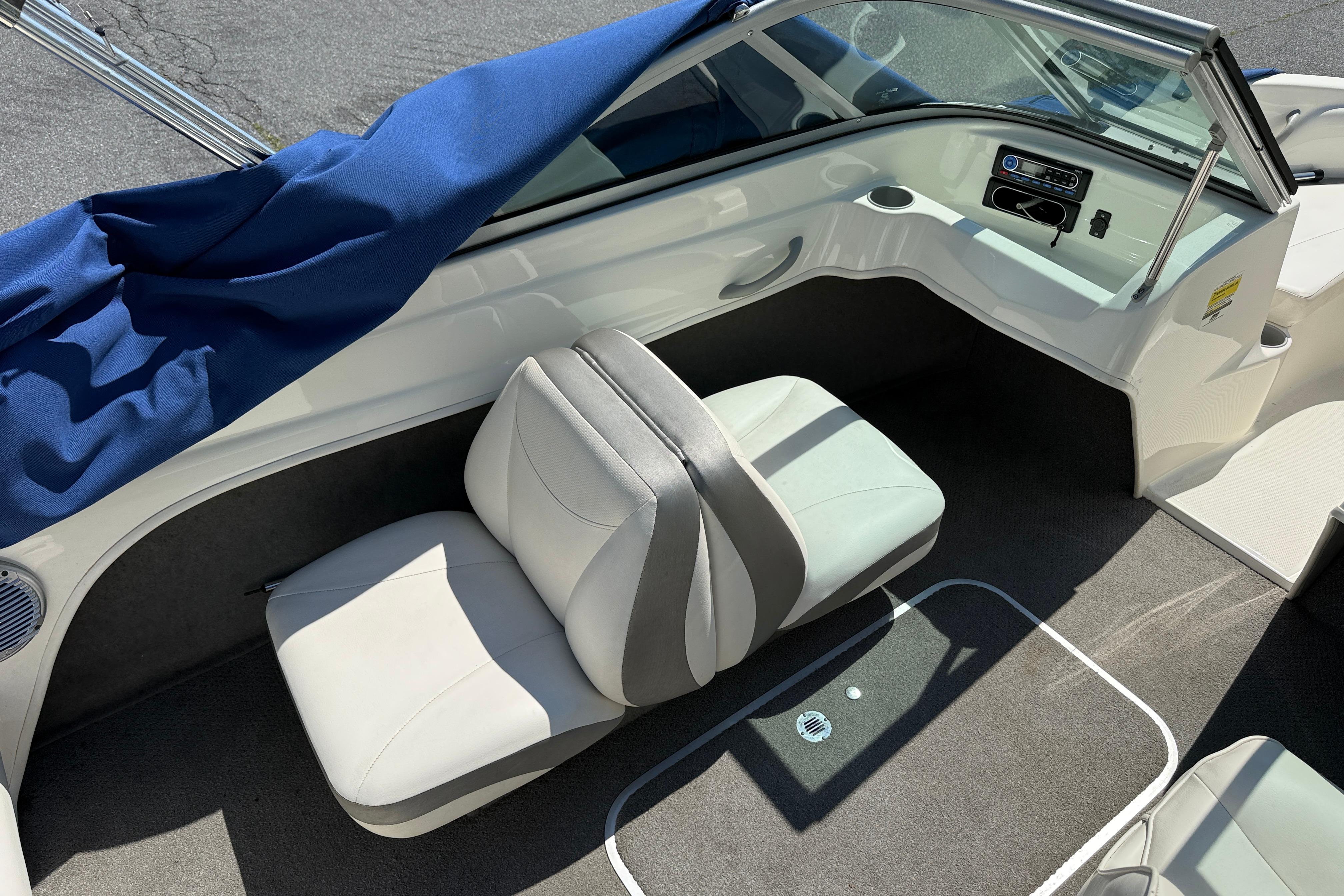 Interior of a 2009 Bayliner 175 boat with white seating and blue cover.
