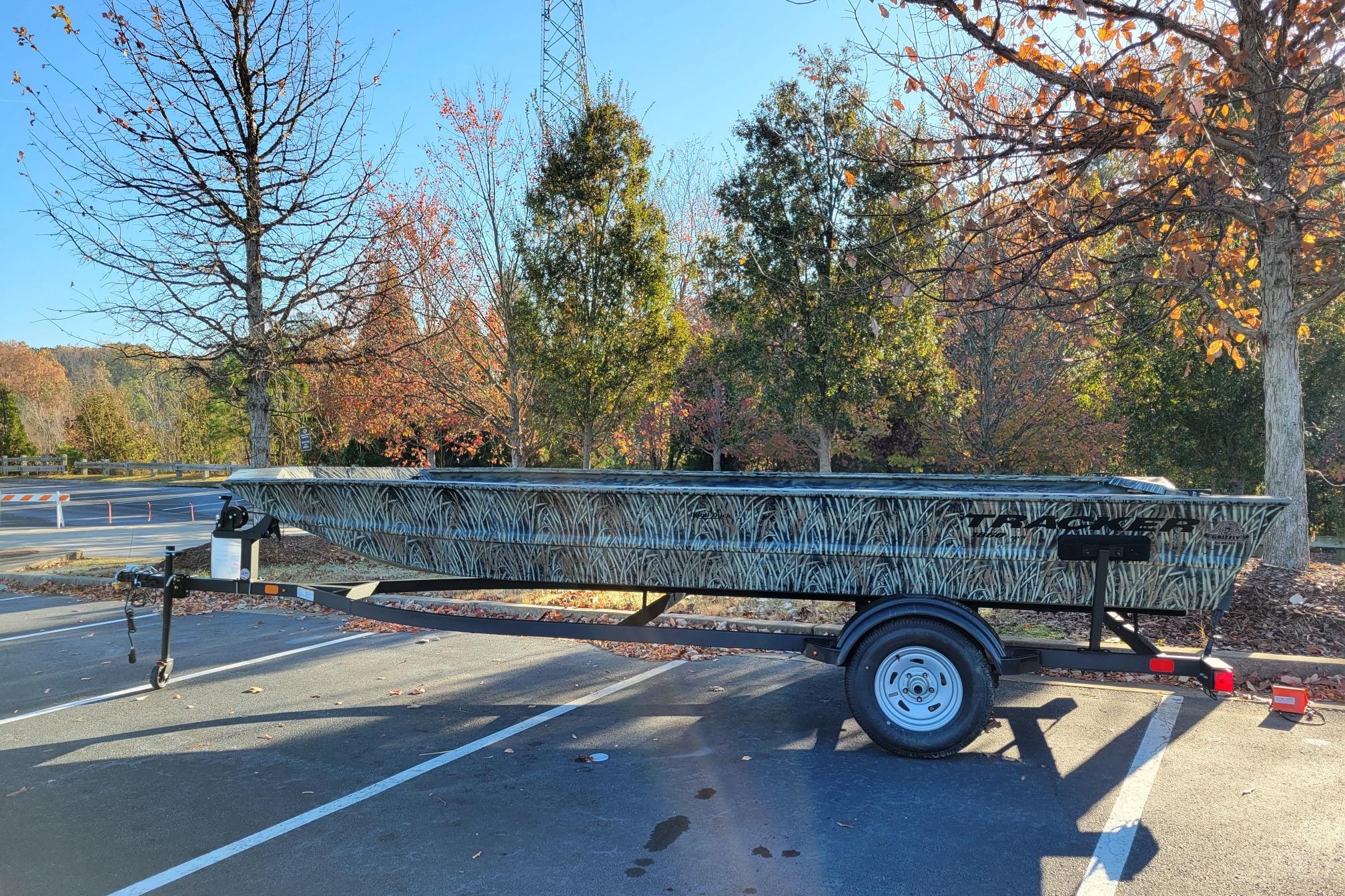 2025 Tracker Grizzly 1860 Utility boat on trailer, parked in autumn setting.