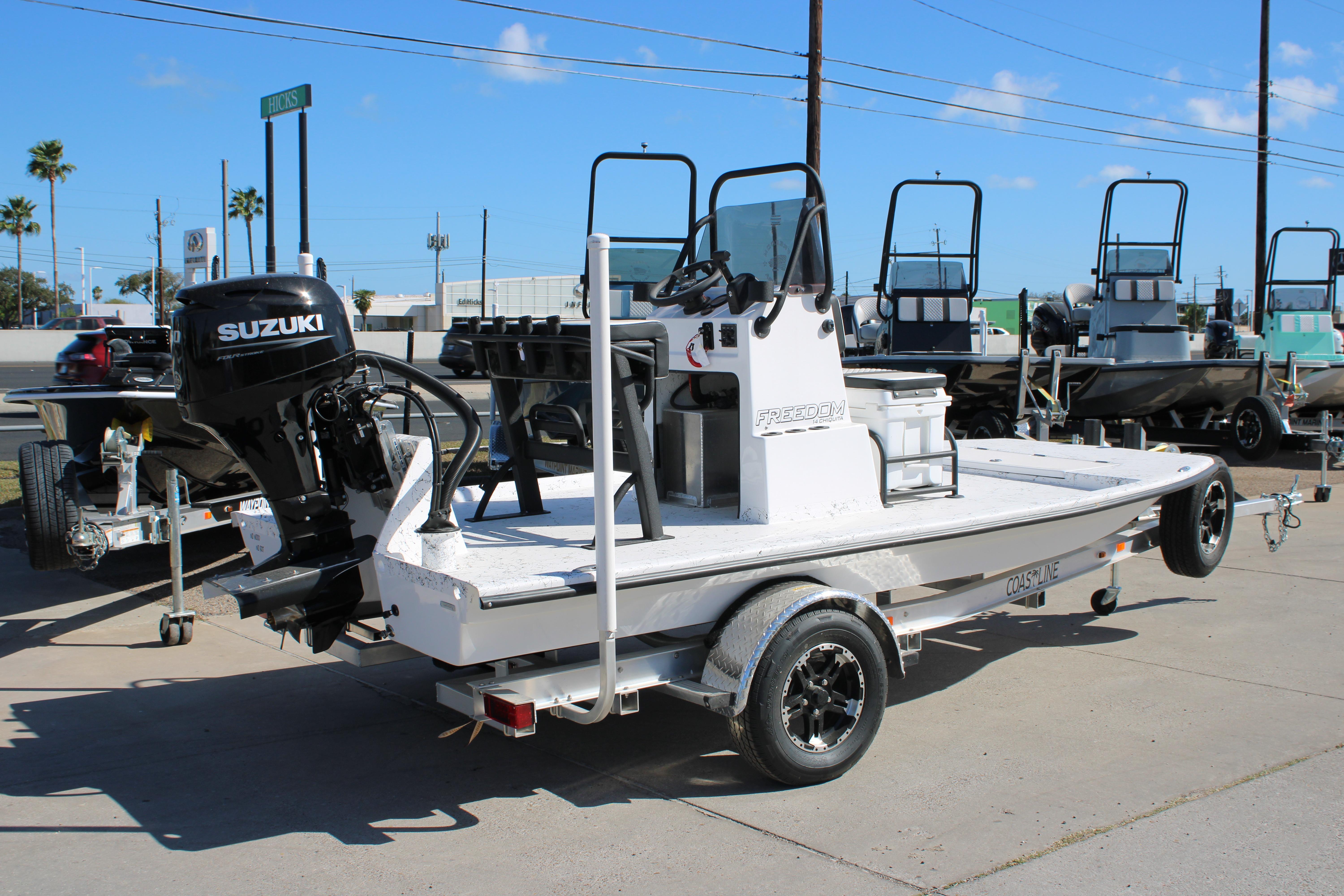 2026 Freedom Boats Chiquita with Suzuki engine on trailer, parked outdoors.