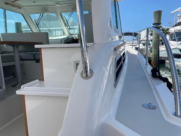 2024 Back Cove 34O yacht exterior, side deck view with railing and cockpit seating.