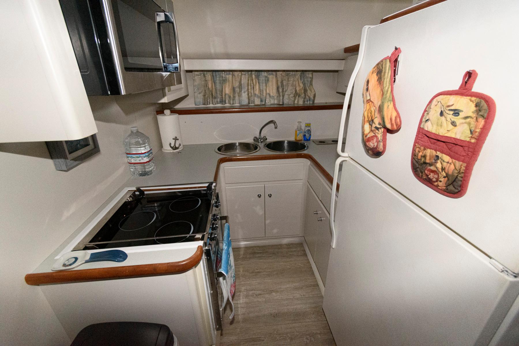 Compact kitchen in 1994 Carver 440 Aft Cabin Motor Yacht with stove, fridge, and microwave.