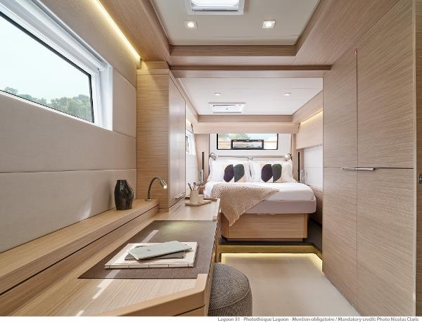 Luxurious interior of 2025 Lagoon 51 ICONIC yacht, featuring a modern bedroom with elegant wood finishes.