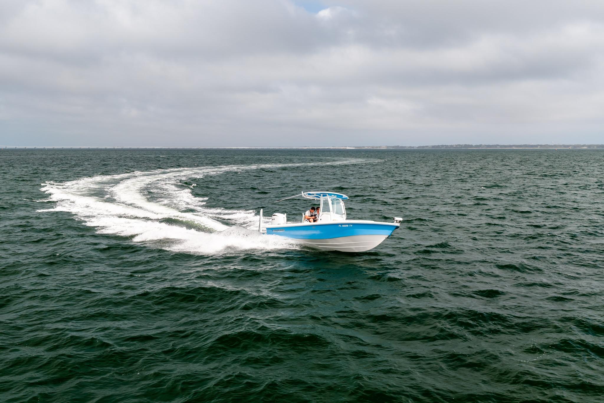 2023 Everglades 243 Center Console boat cruising on open water under cloudy skies.