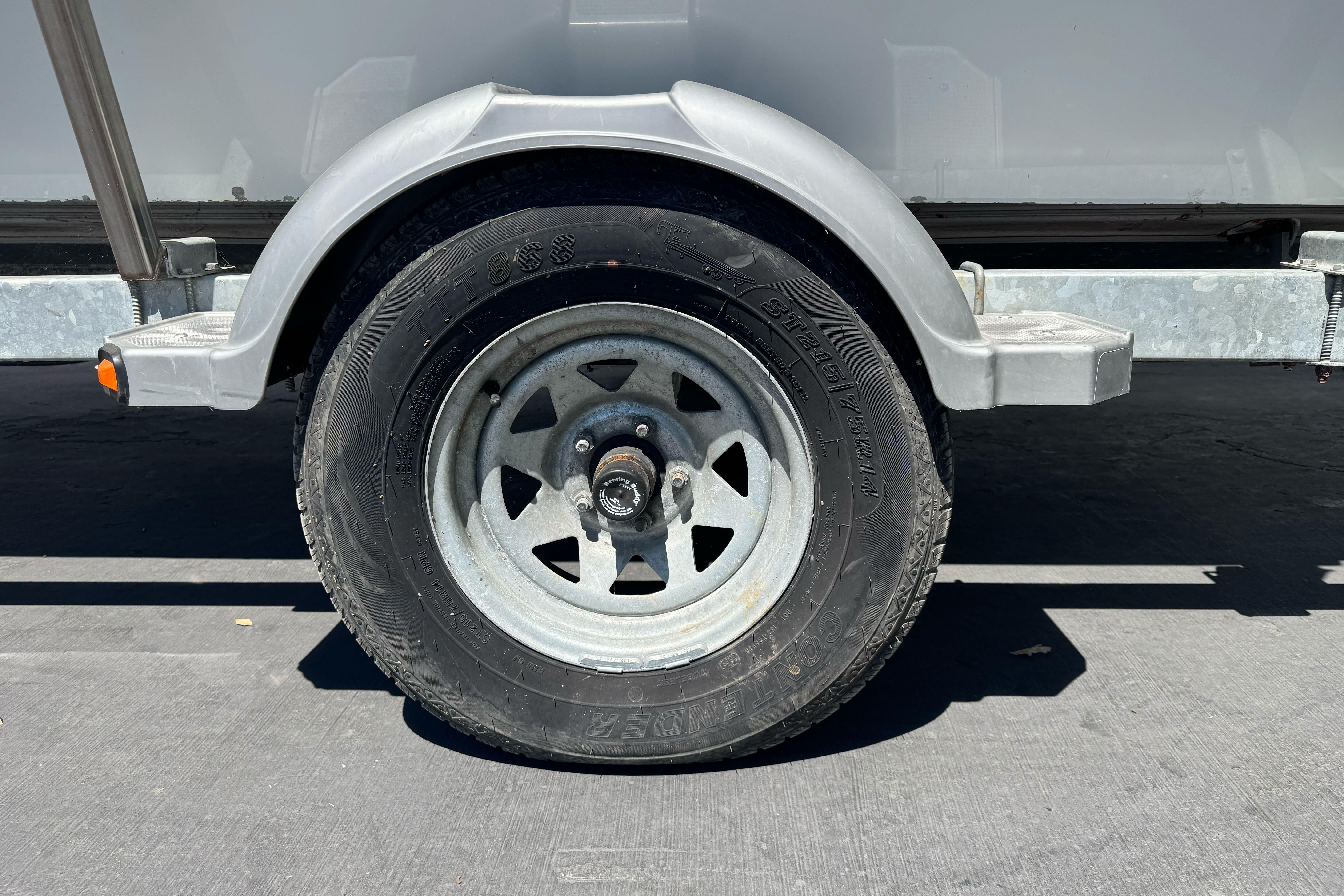 Trailer wheel of a 2014 River Hawk 19 GB boat, parked on pavement.
