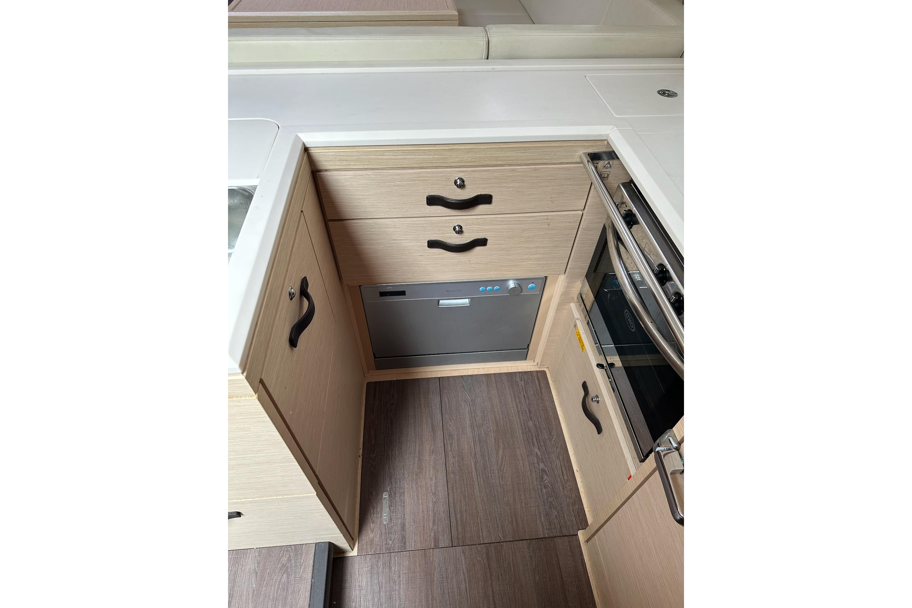 Modern kitchen area in a 2018 Jeanneau 51 yacht with wood cabinetry and appliances.