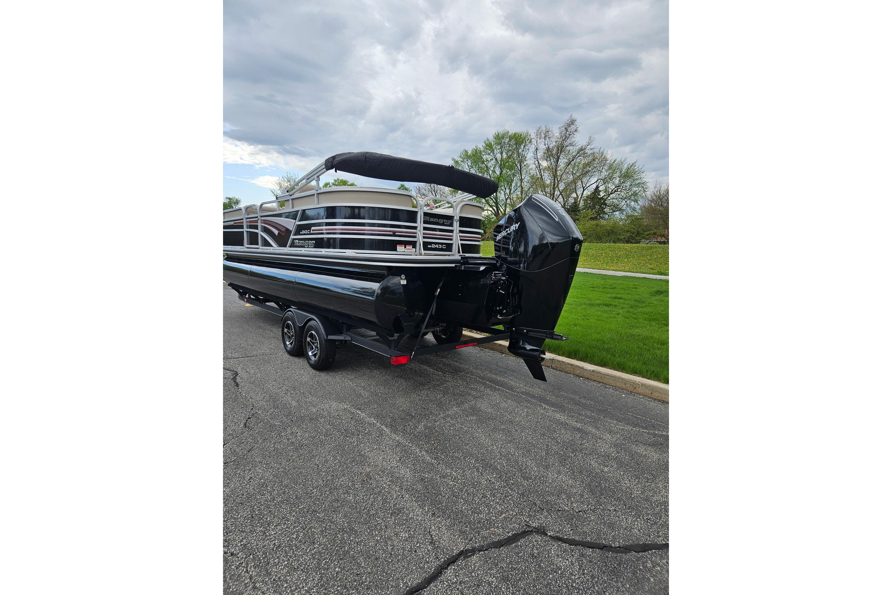 2023 Ranger Reata 243C pontoon boat on trailer, parked on a road.