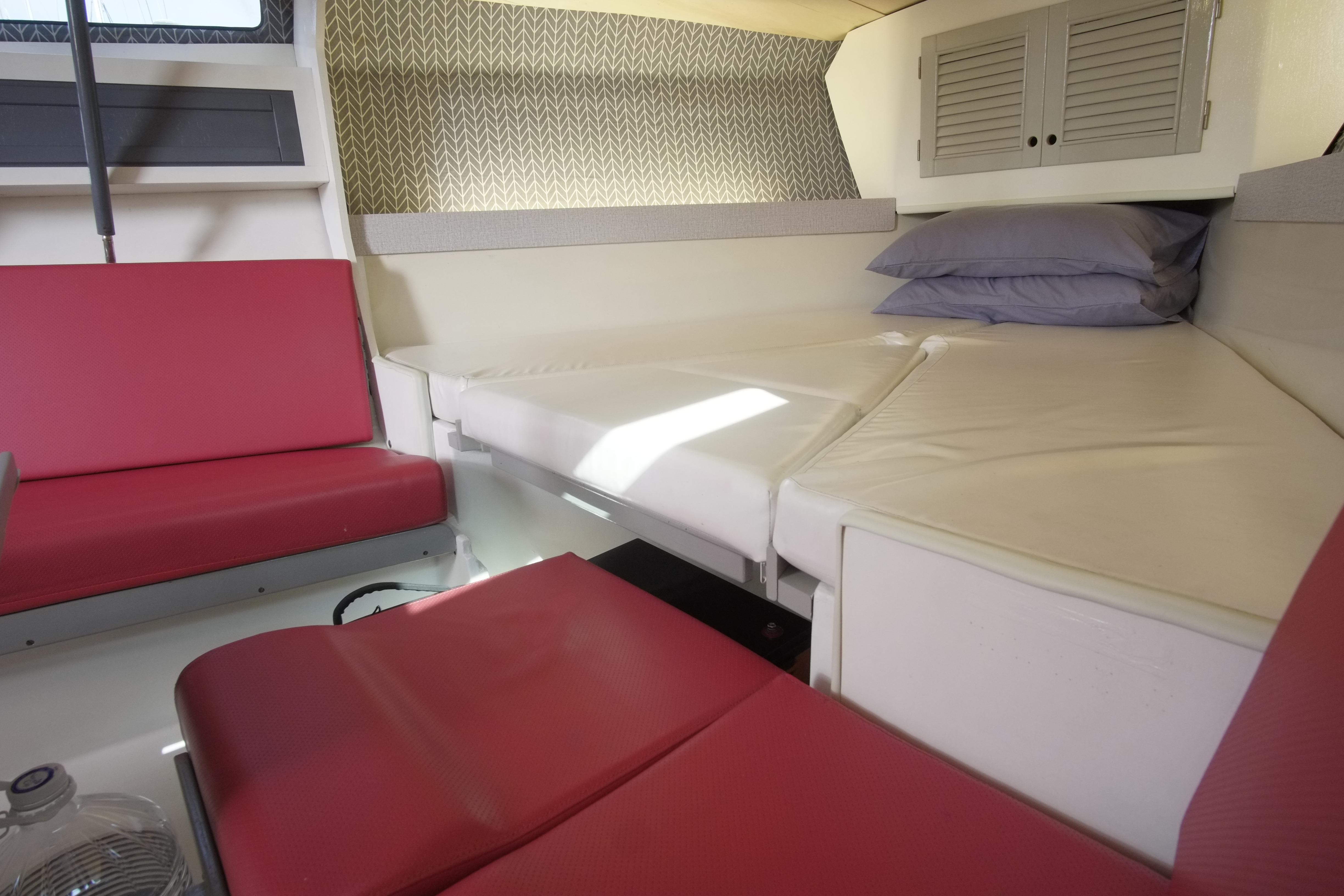 Interior of 1983 Maxi 100 PS boat with red seating and white bedding.