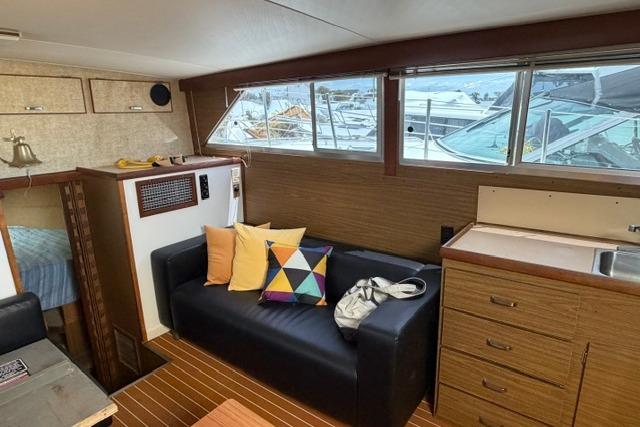 Interior of 1980 Chris-Craft 381 Catalina yacht with sofa, colorful pillows, and kitchenette.