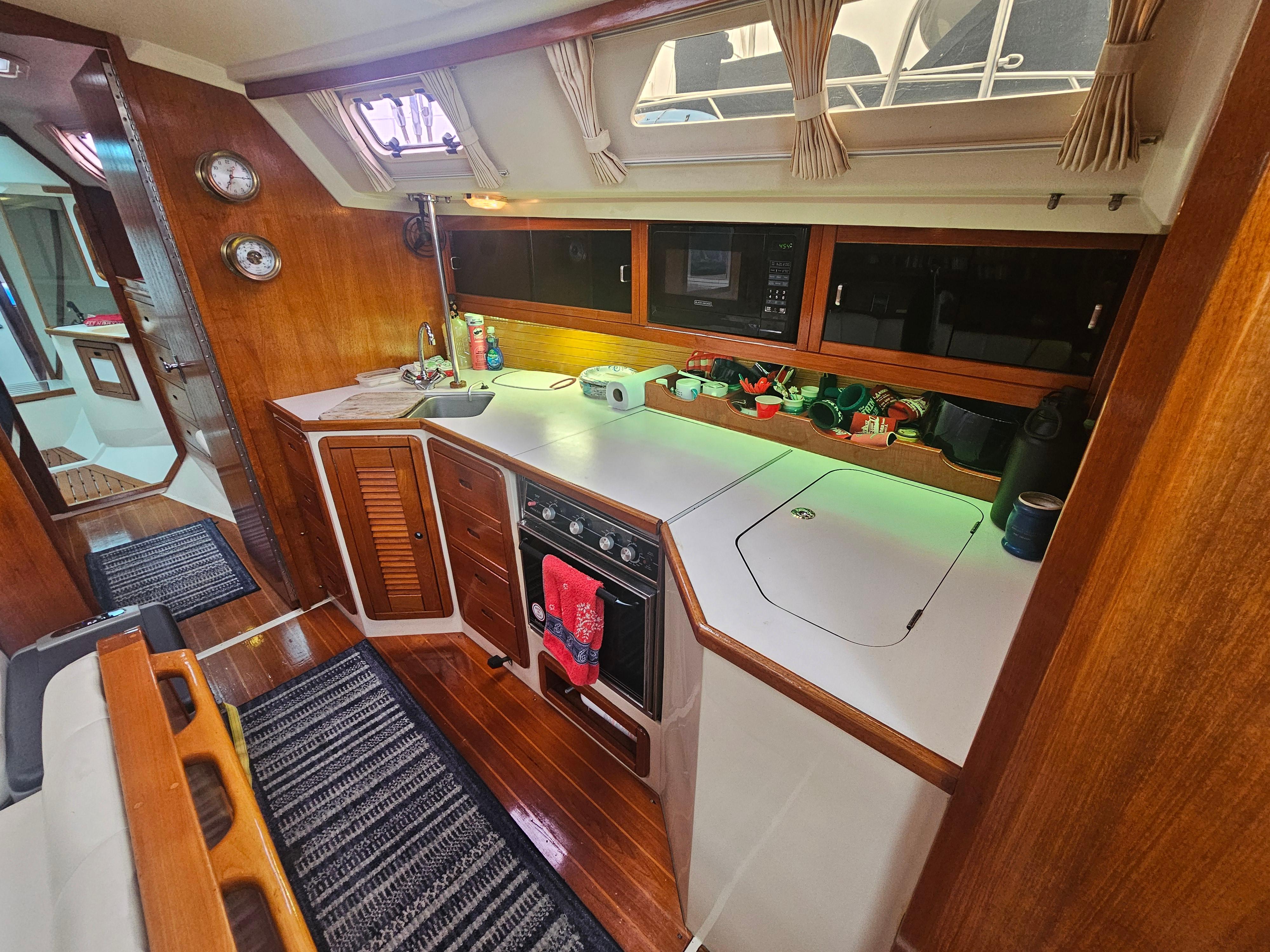 Interior of a 1990 Catalina 42 sailboat kitchen with wooden cabinetry and modern appliances.