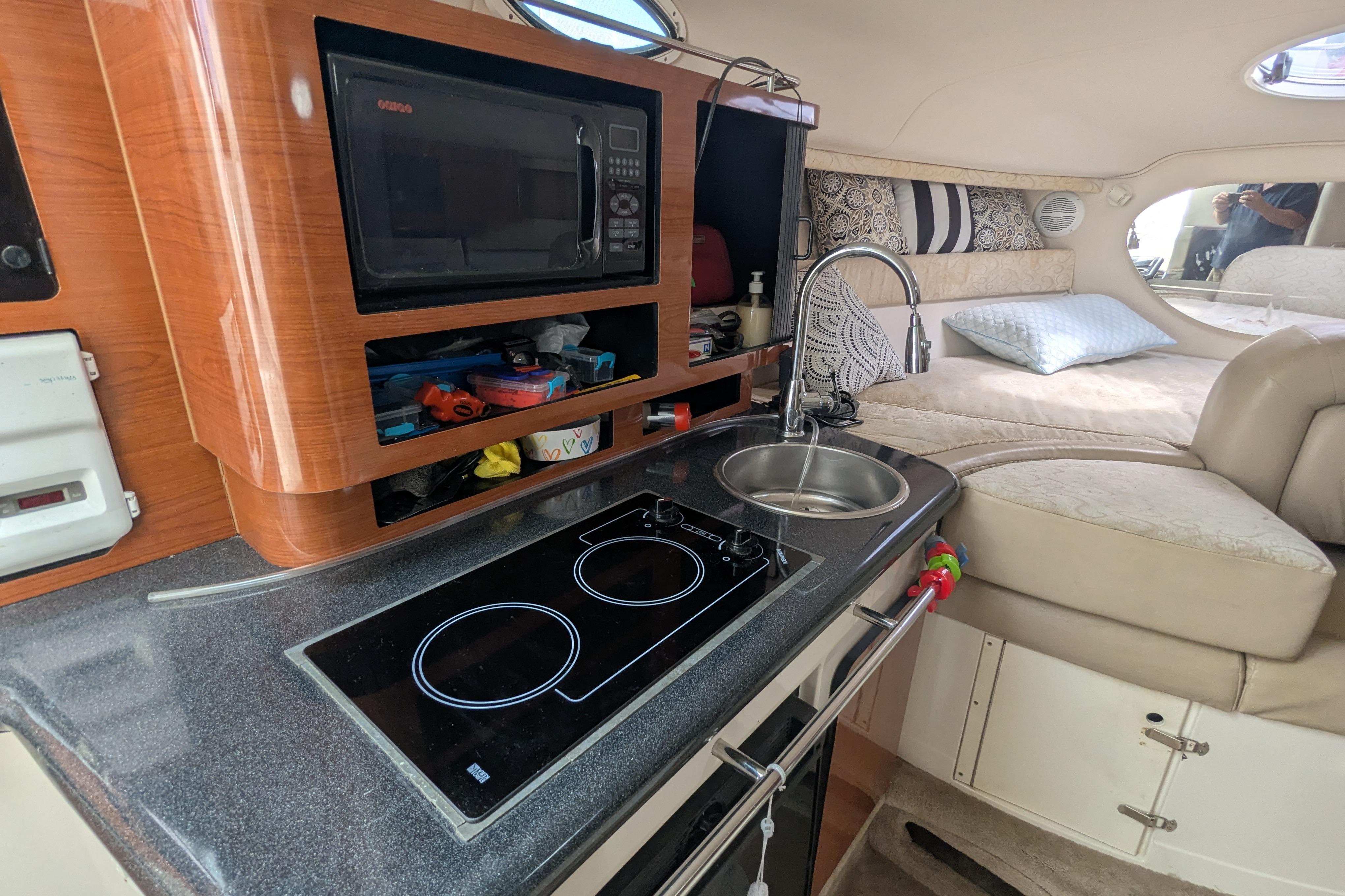 2003 Monterey 282 Cruiser interior with kitchenette, microwave, stove, sink, and cozy sleeping area.