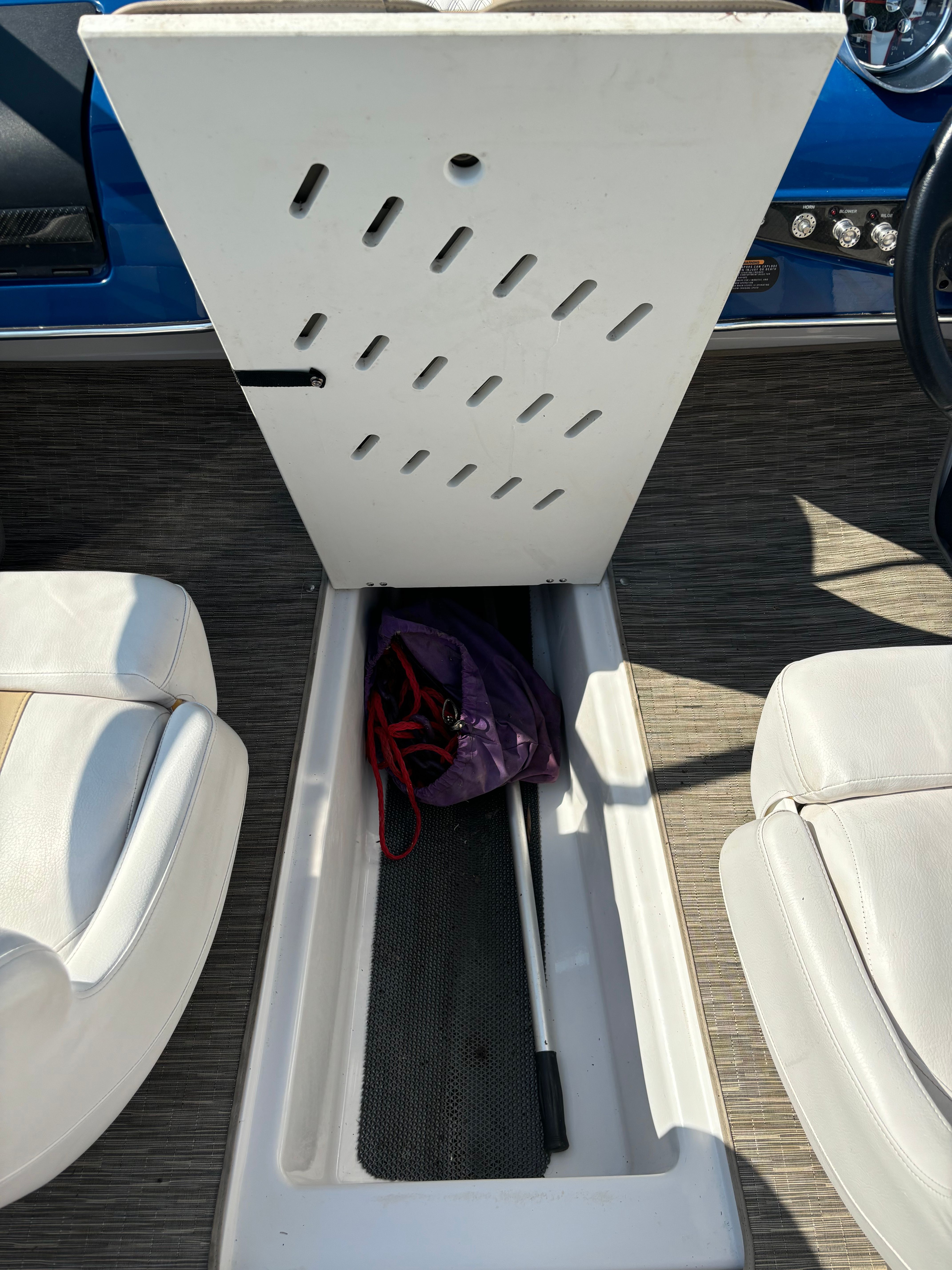 An open storage compartment on a boat with a purple bag inside.
