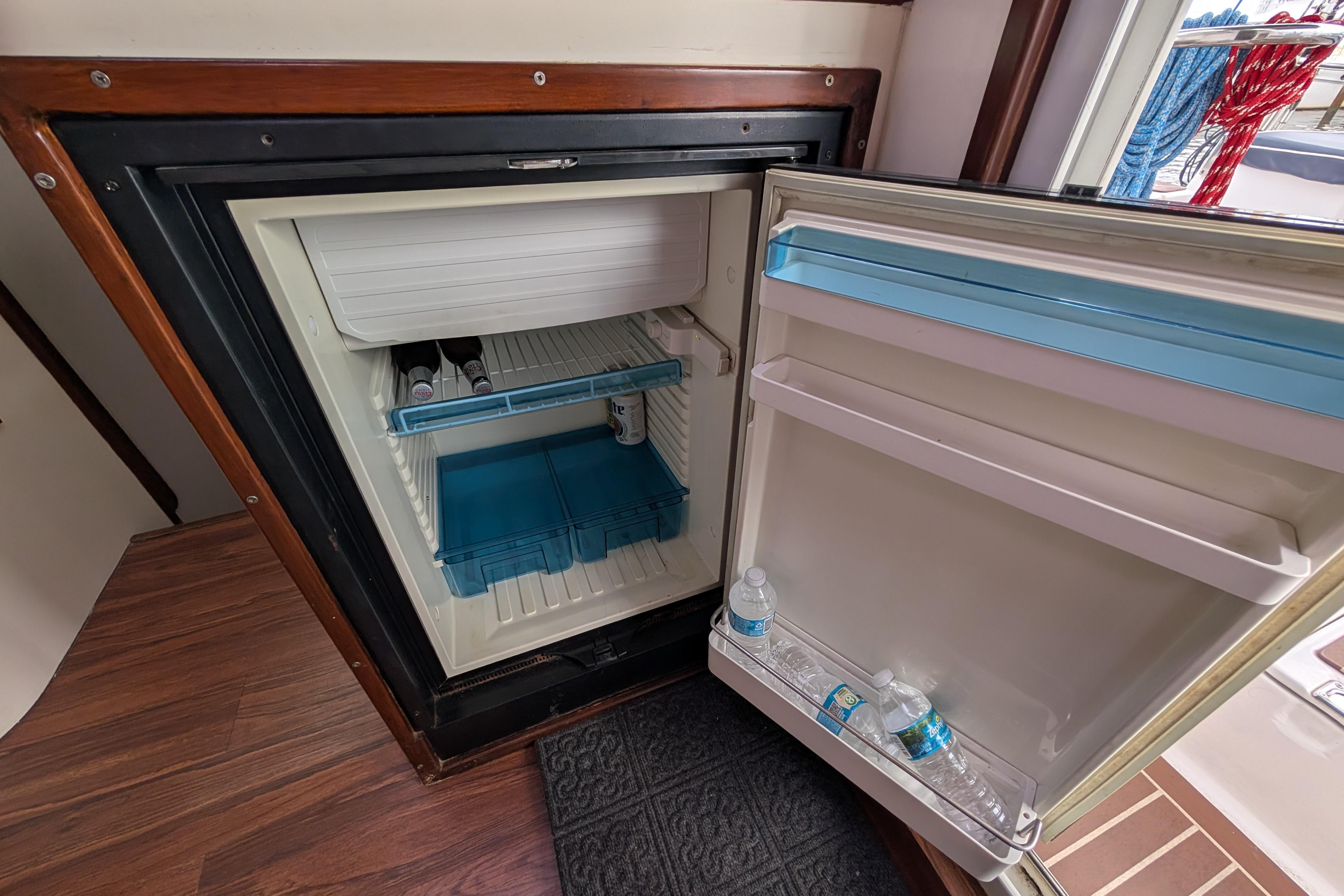 Open refrigerator on Island Spirit 37 yacht, stocked with drinks, showcasing interior storage.