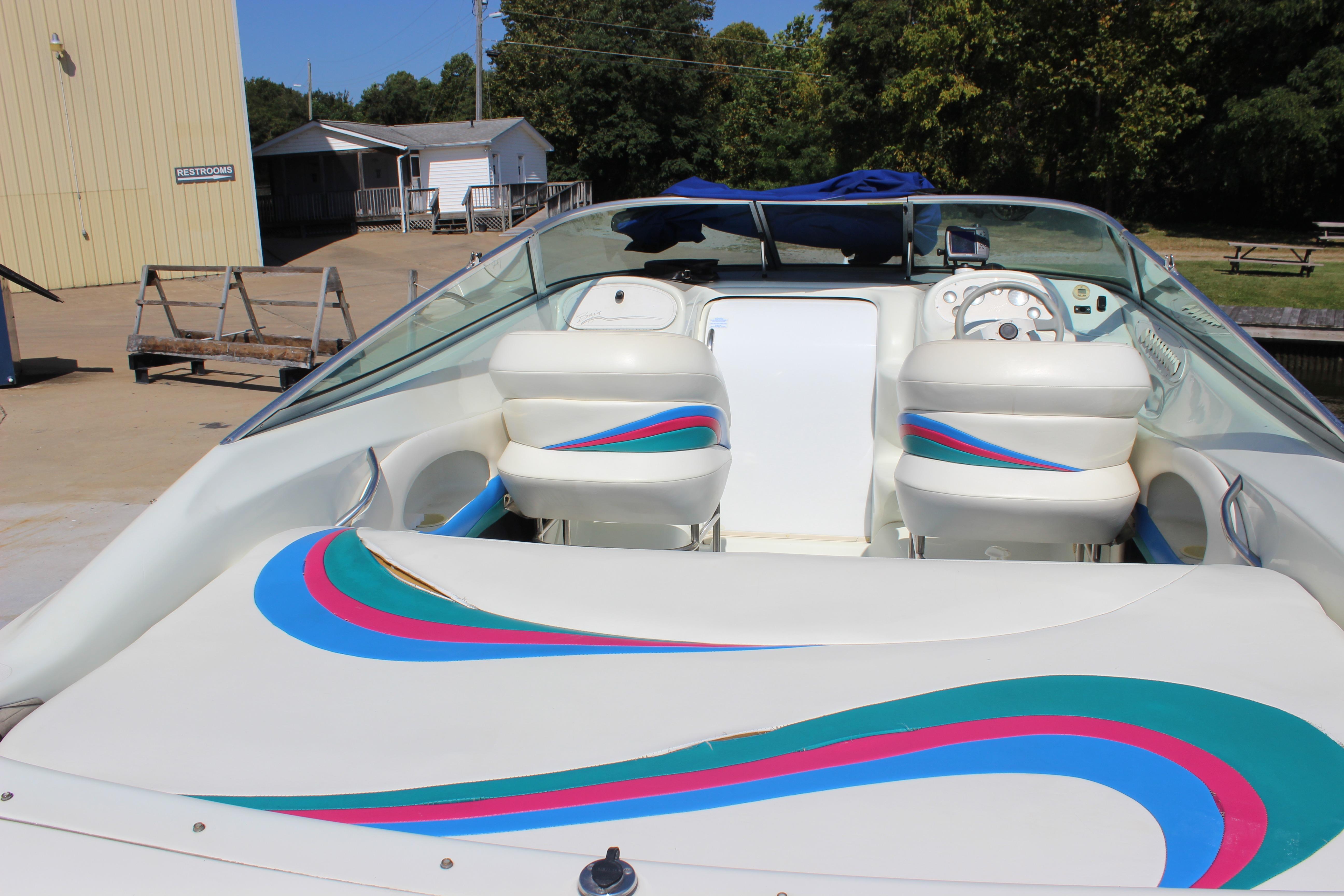1995 Baja 272 boat interior with colorful seating and dashboard, docked near a building.