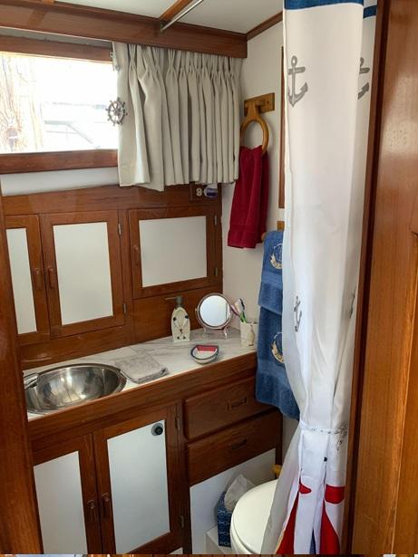 1985 Roughwater 36 boat bathroom with wooden cabinets, nautical decor, and stainless steel sink.