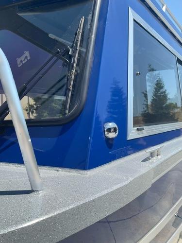 2025 Spartan 240 Maximus Pro boat, blue exterior, close-up of window and railing.