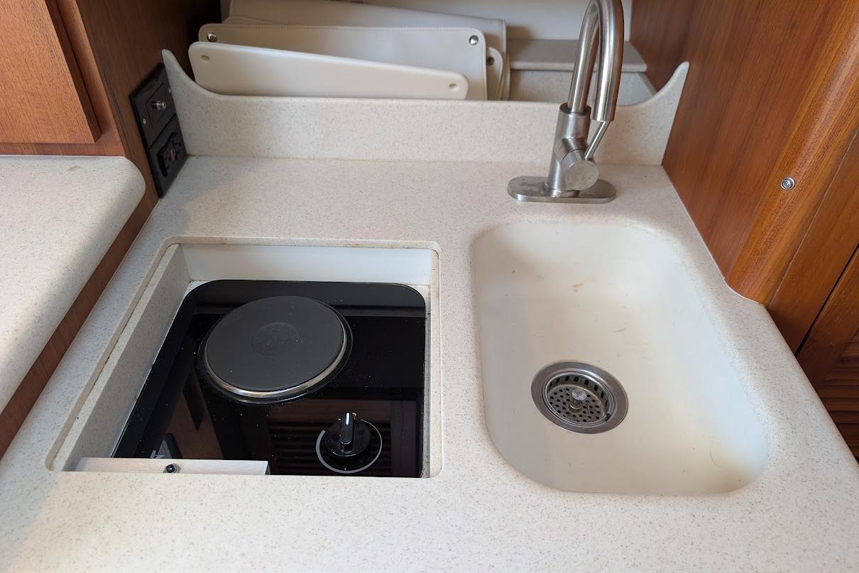 Compact kitchen area in a 2000 Pursuit 3400 Express boat with sink and stove.