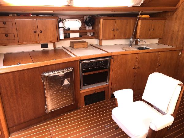 Interior of 2001 Jeanneau 45.2 yacht kitchen with wooden cabinets and appliances.