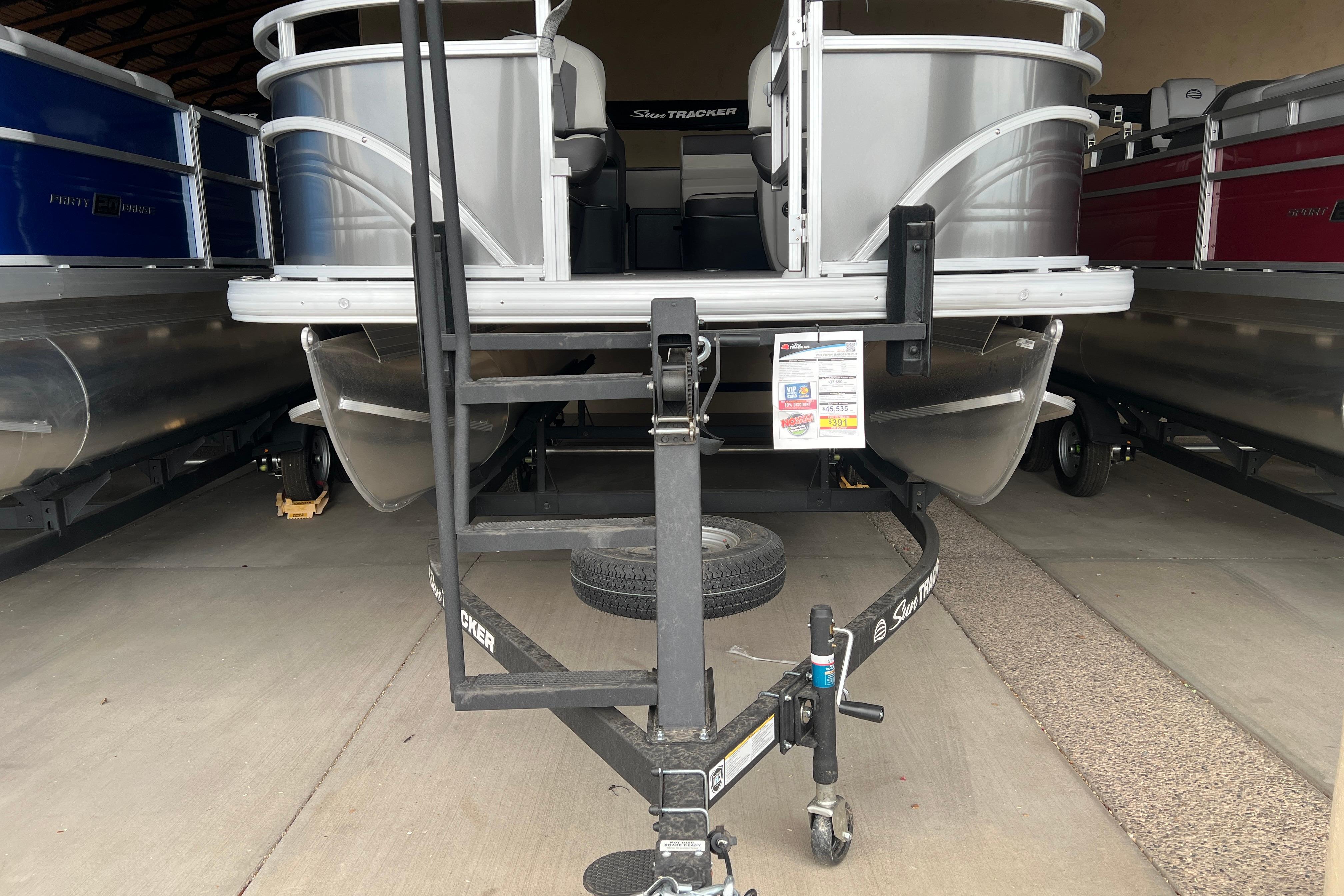 2026 Sun Tracker Fishin' Barge 20 DLX pontoon boat on trailer in storage.