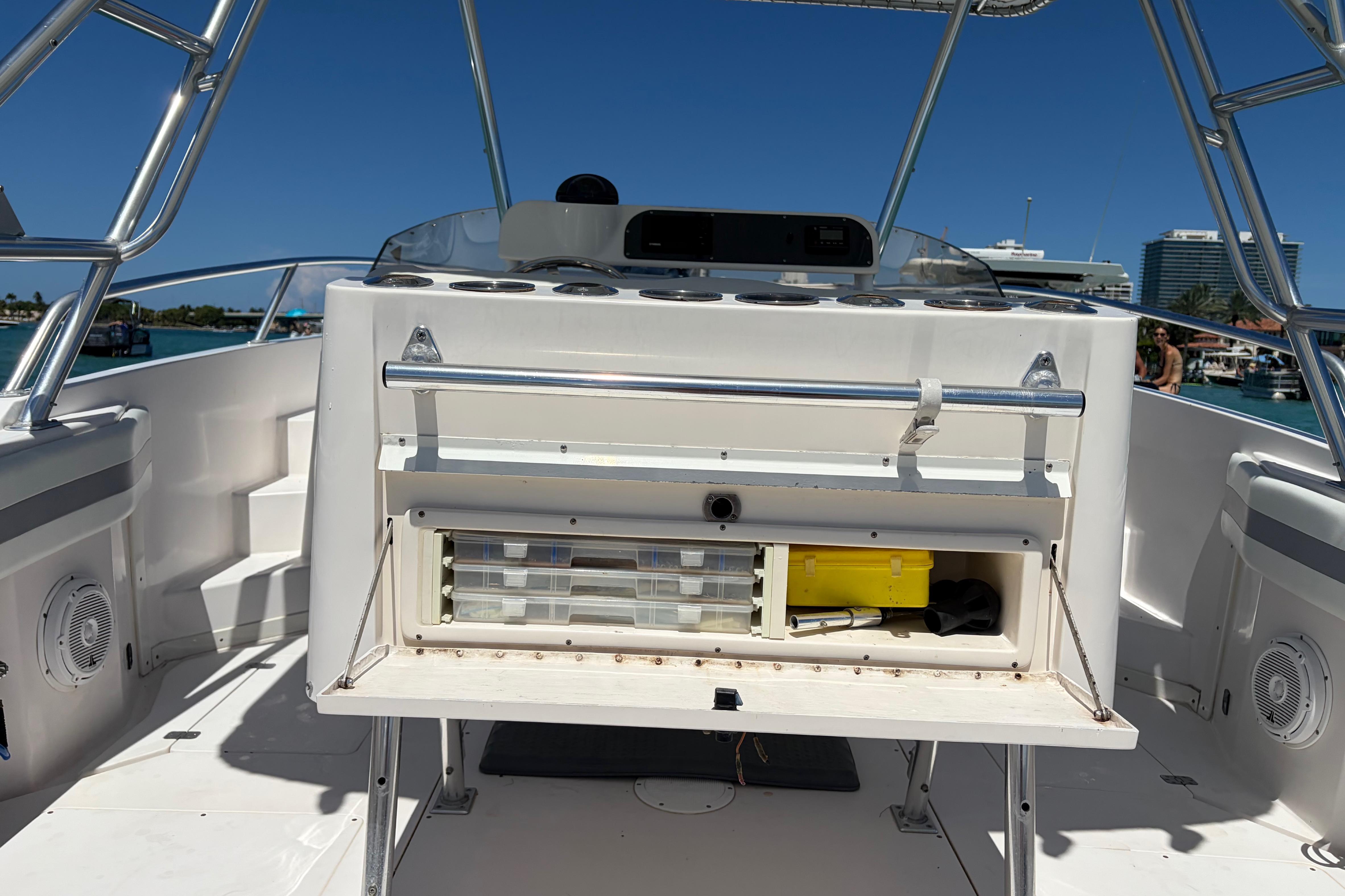 1998 Intrepid 339 Walkaround boat interior with open storage compartment, docked under clear blue sky.