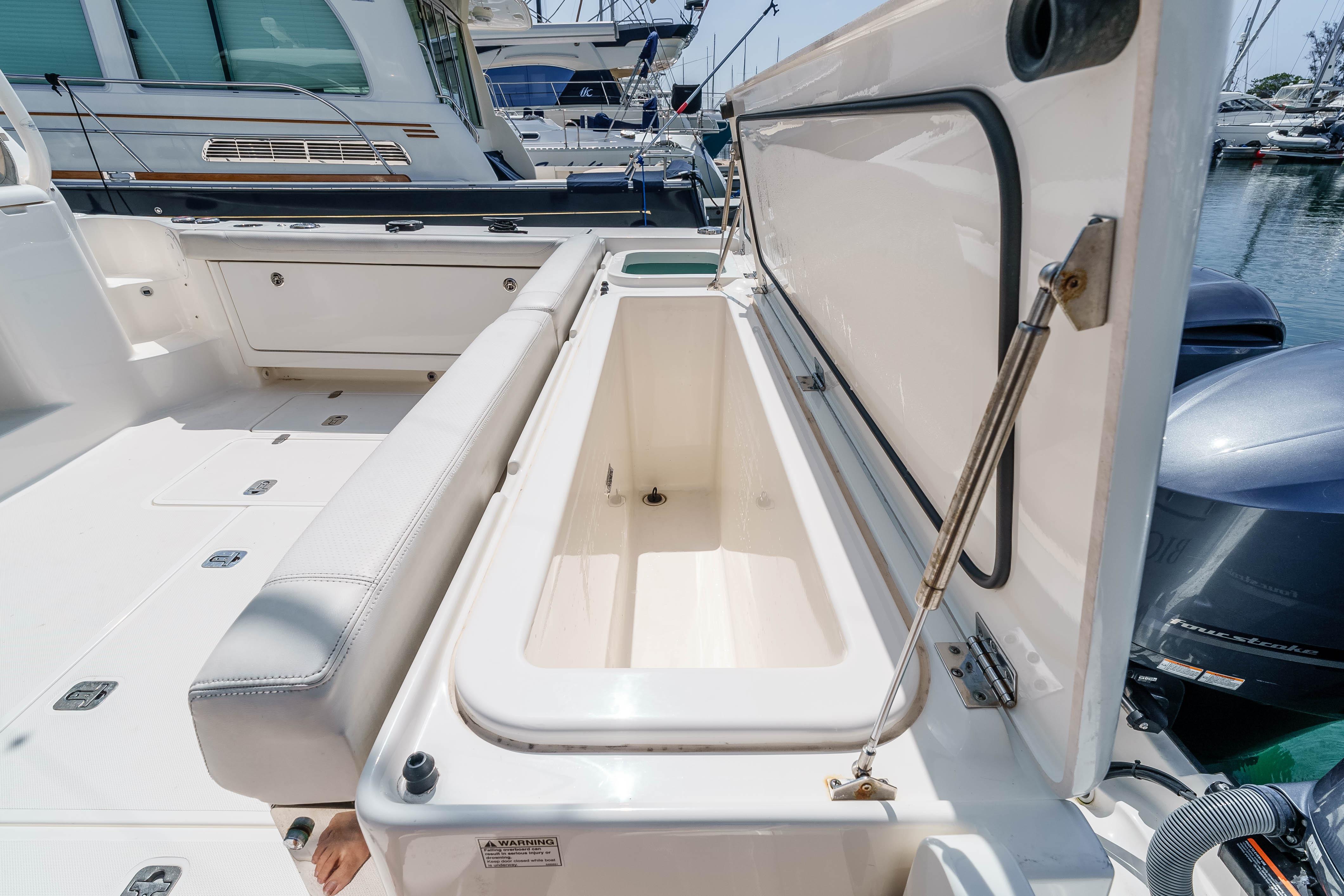 2022 Pursuit OS 385 Offshore boat with open storage compartment in marina setting.