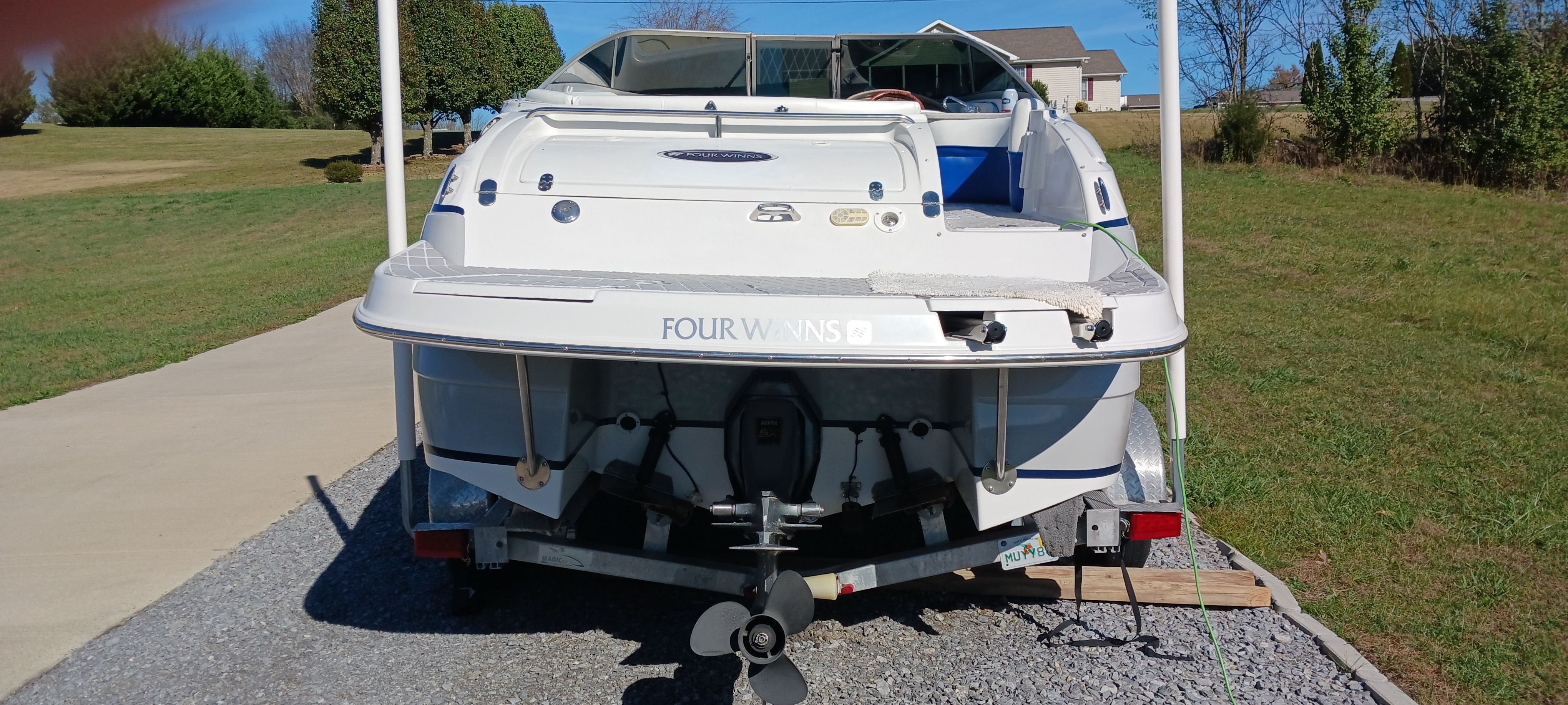 2003 Four Winns 205 Sundowner boat on trailer, parked outdoors on a sunny day.