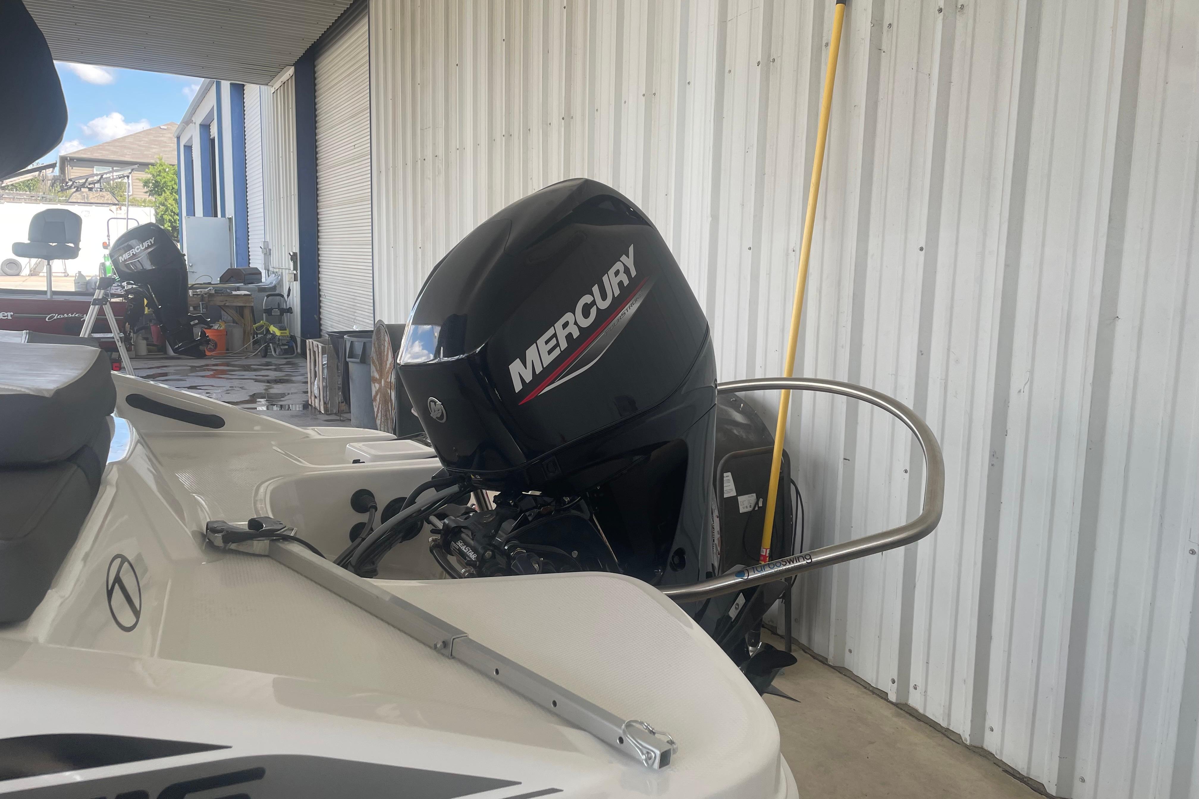 2026 Tahoe T16 boat with Mercury outboard motor in a garage setting.