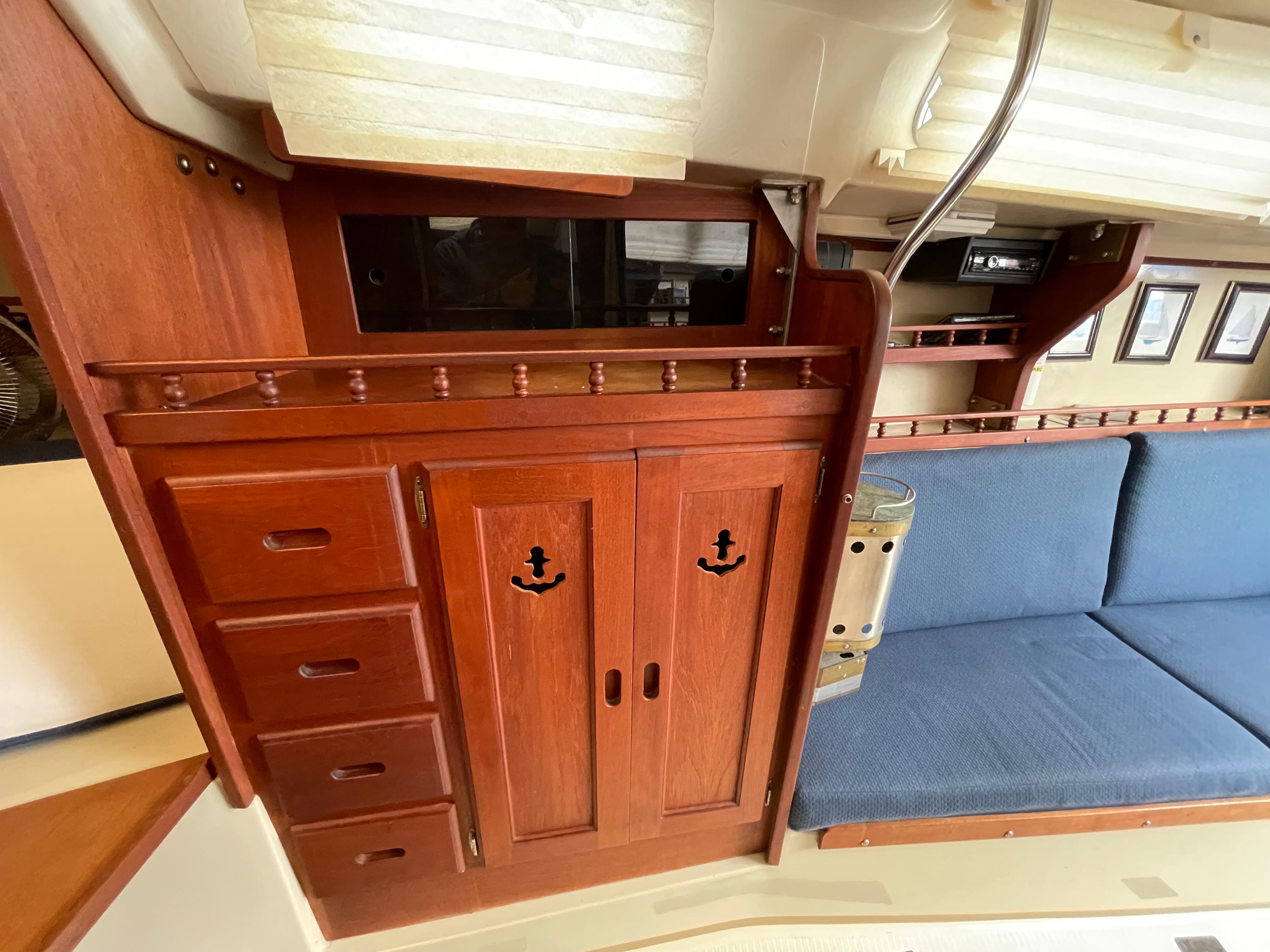 1984 Catalina 30 interior with wooden cabinets and blue cushioned seating.