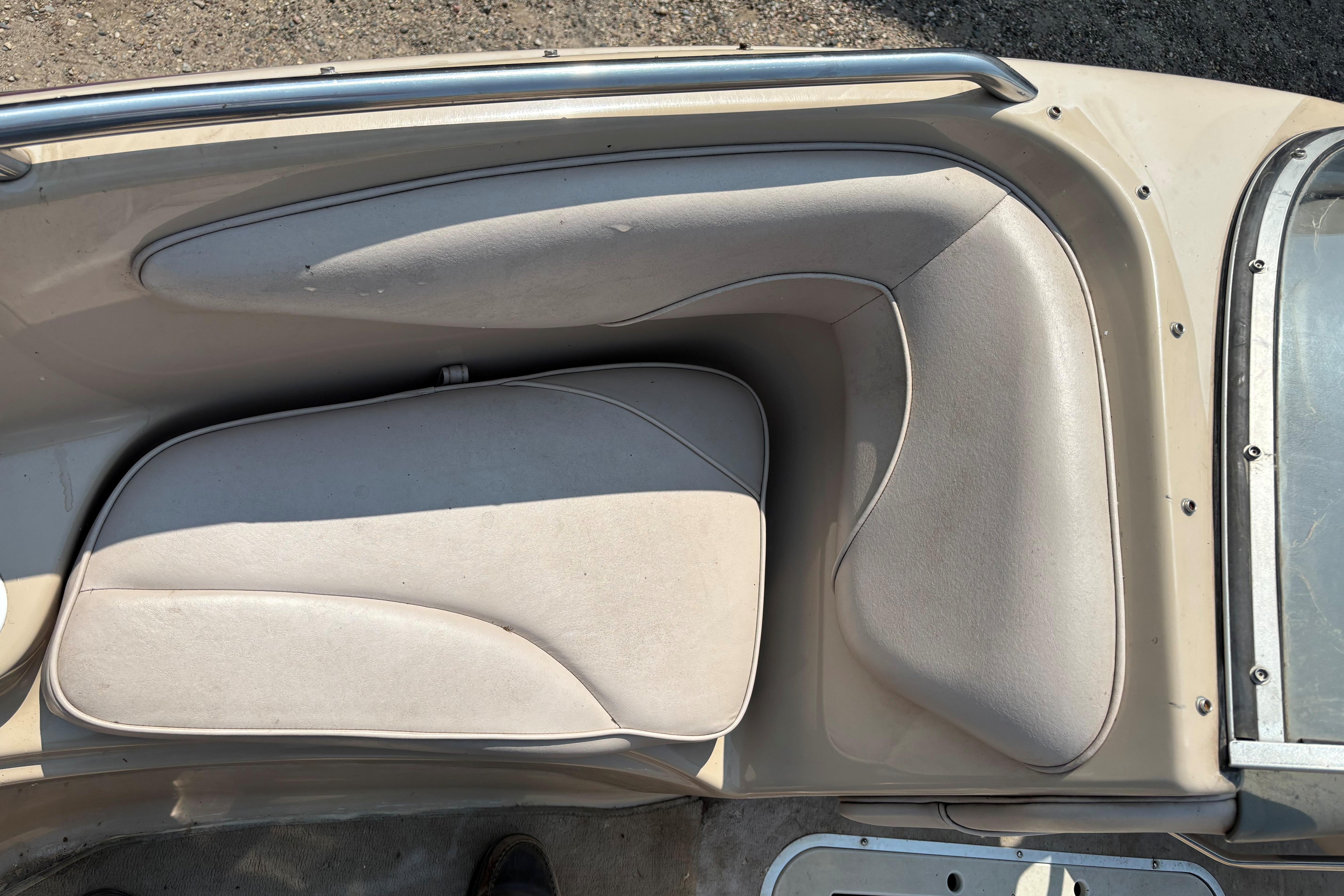 Crownline 18' 2001 boat interior seating with beige upholstery and metal railing.