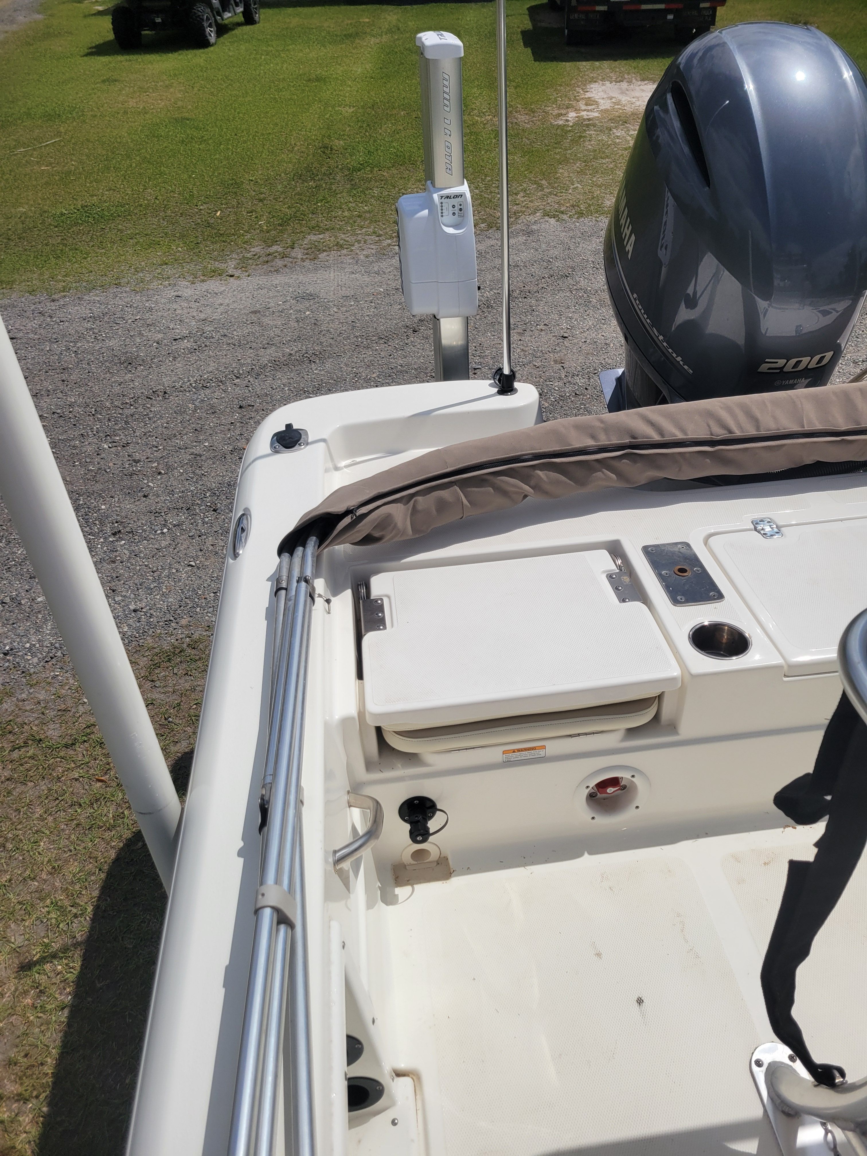 A boat with a Yamaha engine is on a trailer in a grassy area.