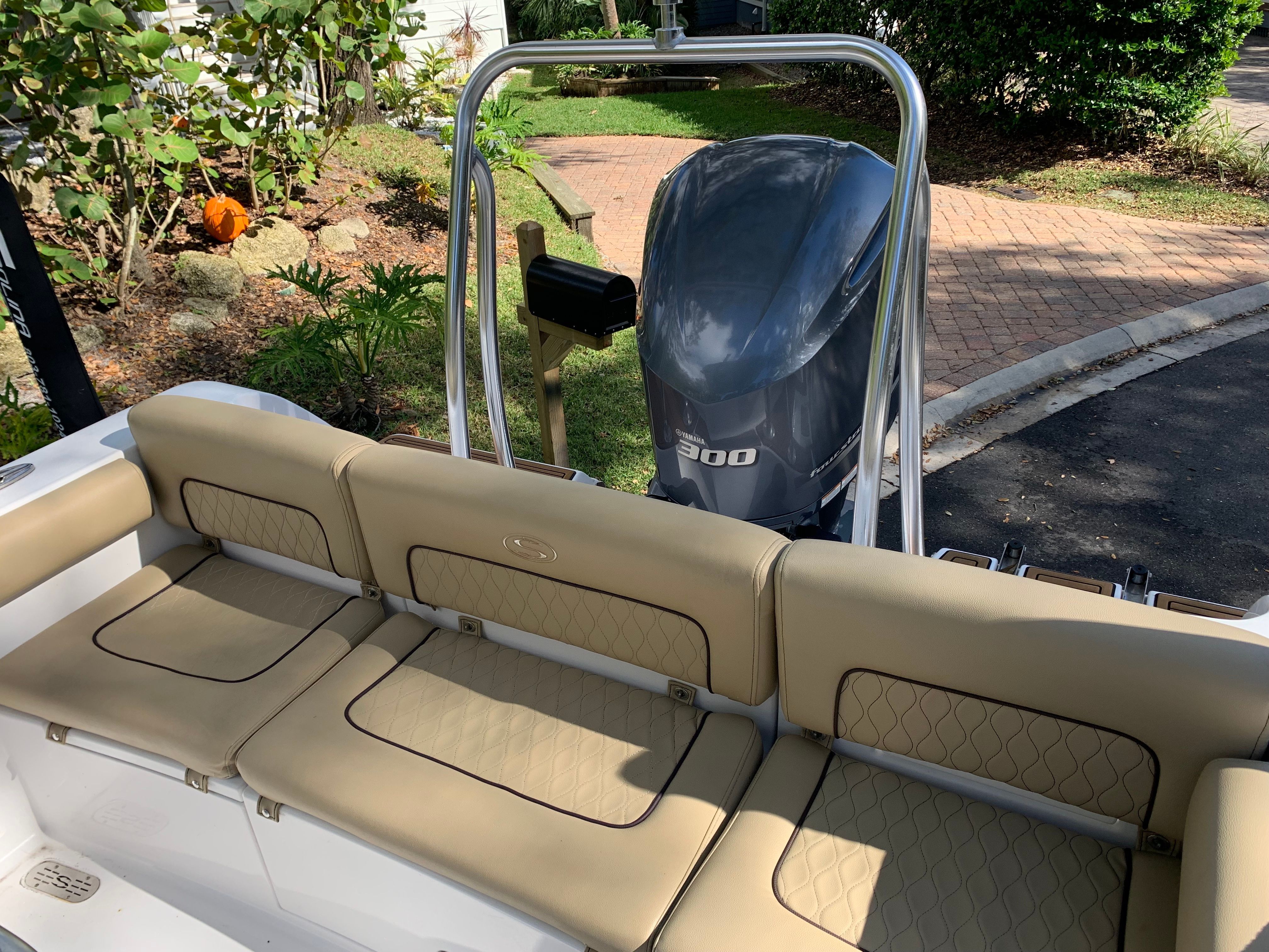 The image shows the stern of a 2018 Sportsman Heritage 241 Center Console boat with beige seating and an outboard motor.