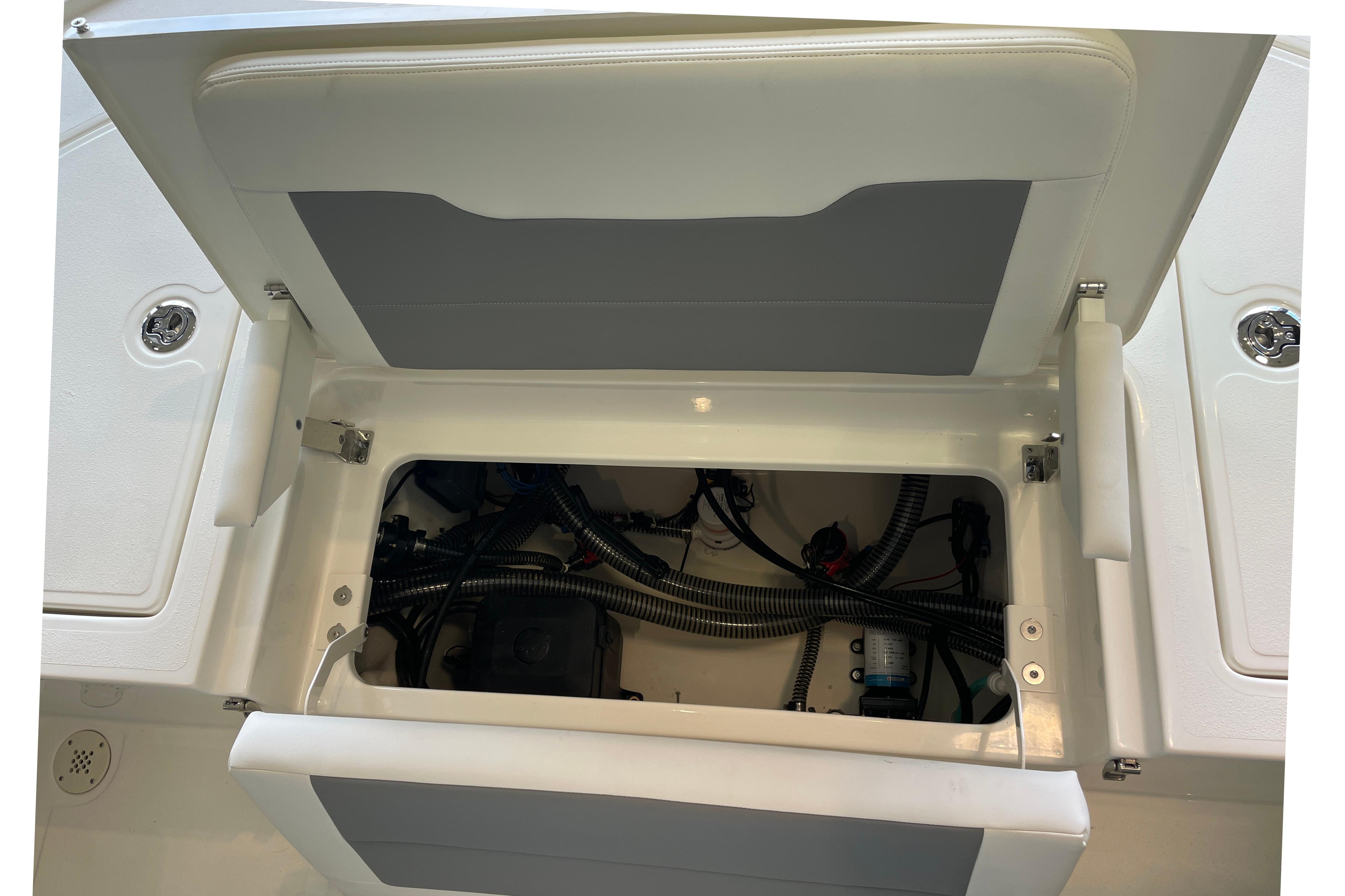 Open storage compartment in 2026 Mako 24 APEX boat, showing internal wiring and components.