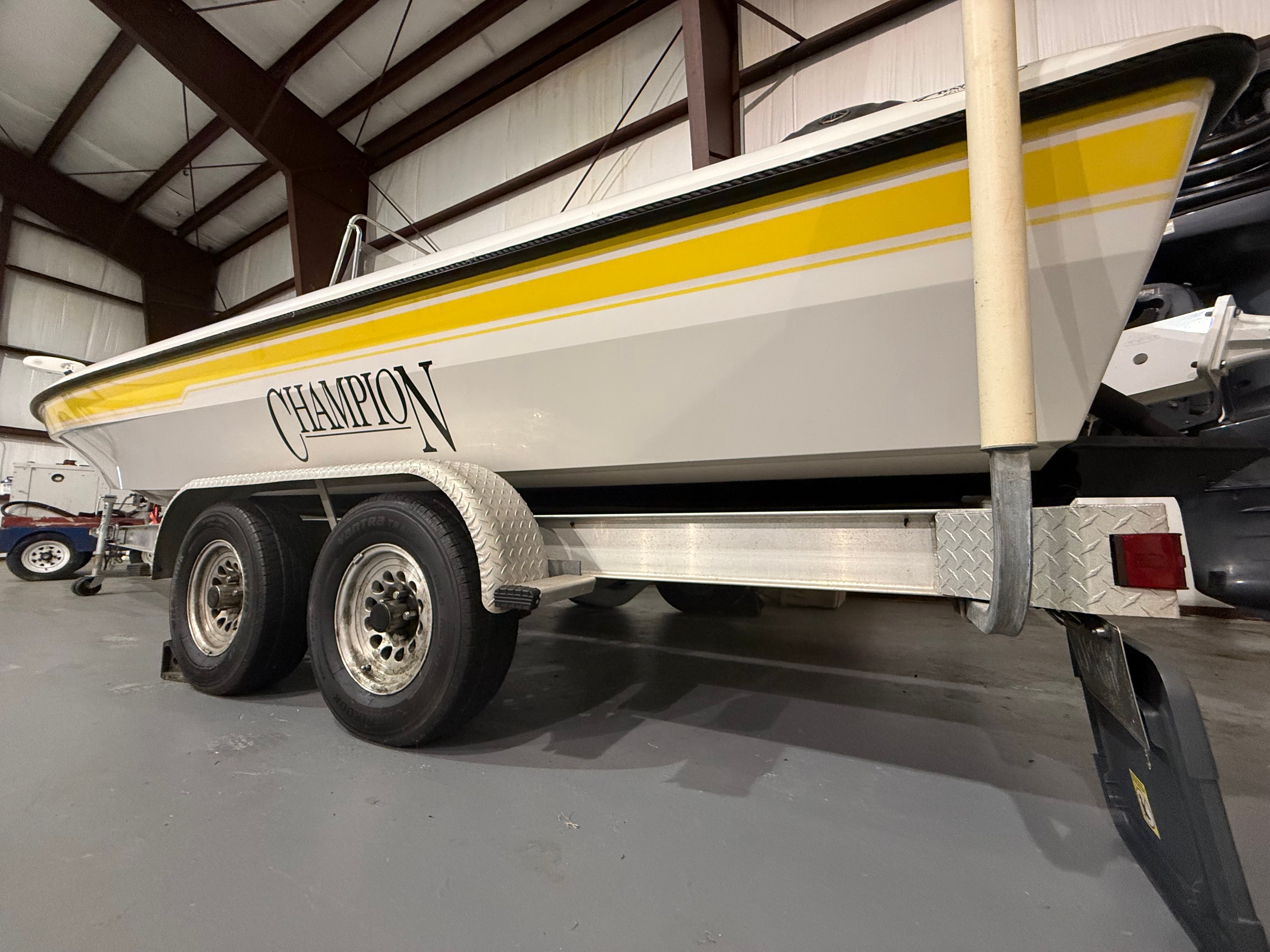 A 2004 Champion 24 Bay Champ boat on a trailer inside a warehouse.