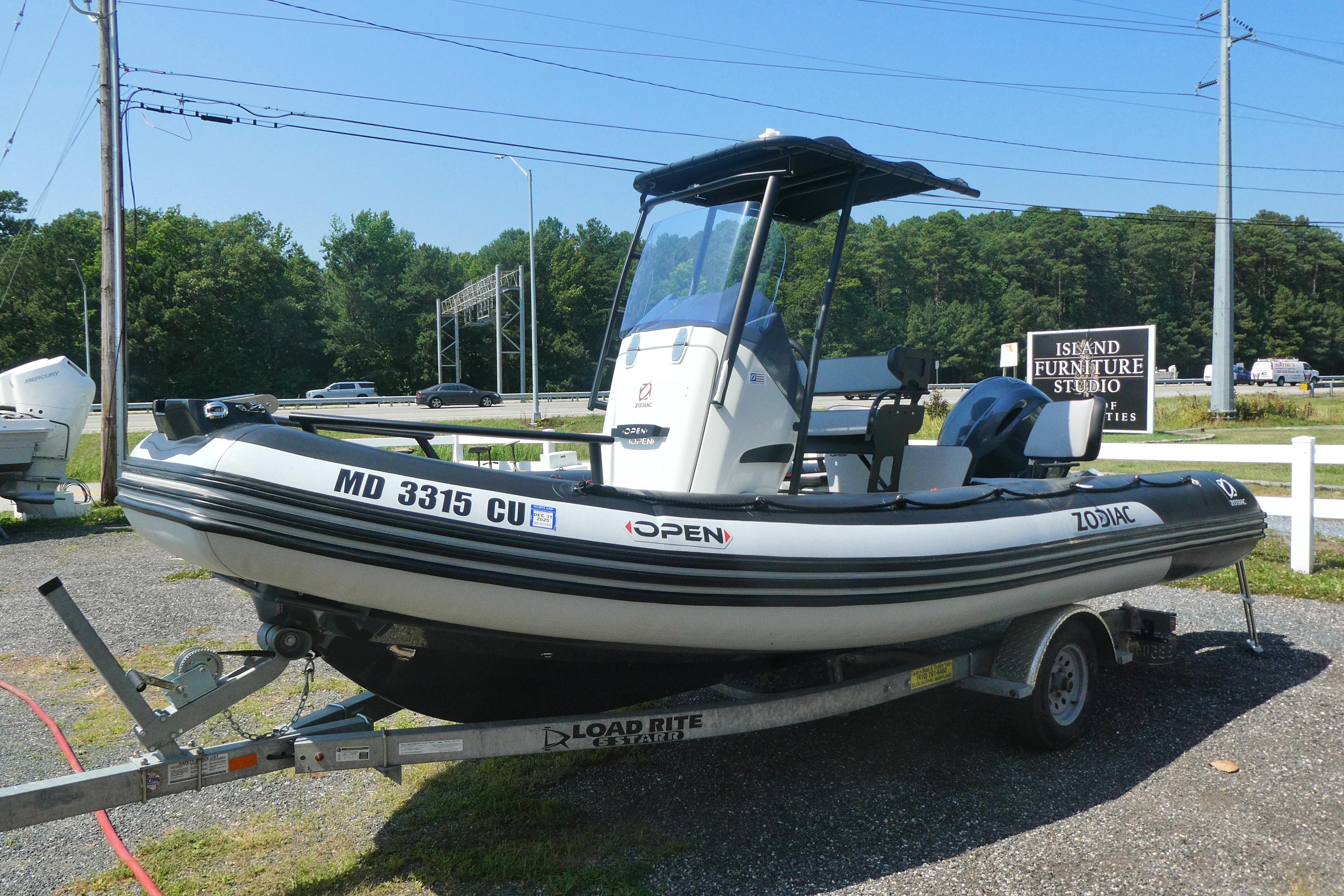 2022 Zodiac Pro 5.5 boat on trailer, parked outdoors near furniture store.