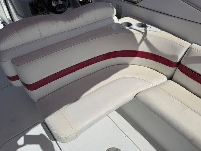 The interior of a boat with white and red upholstery and cup holders.