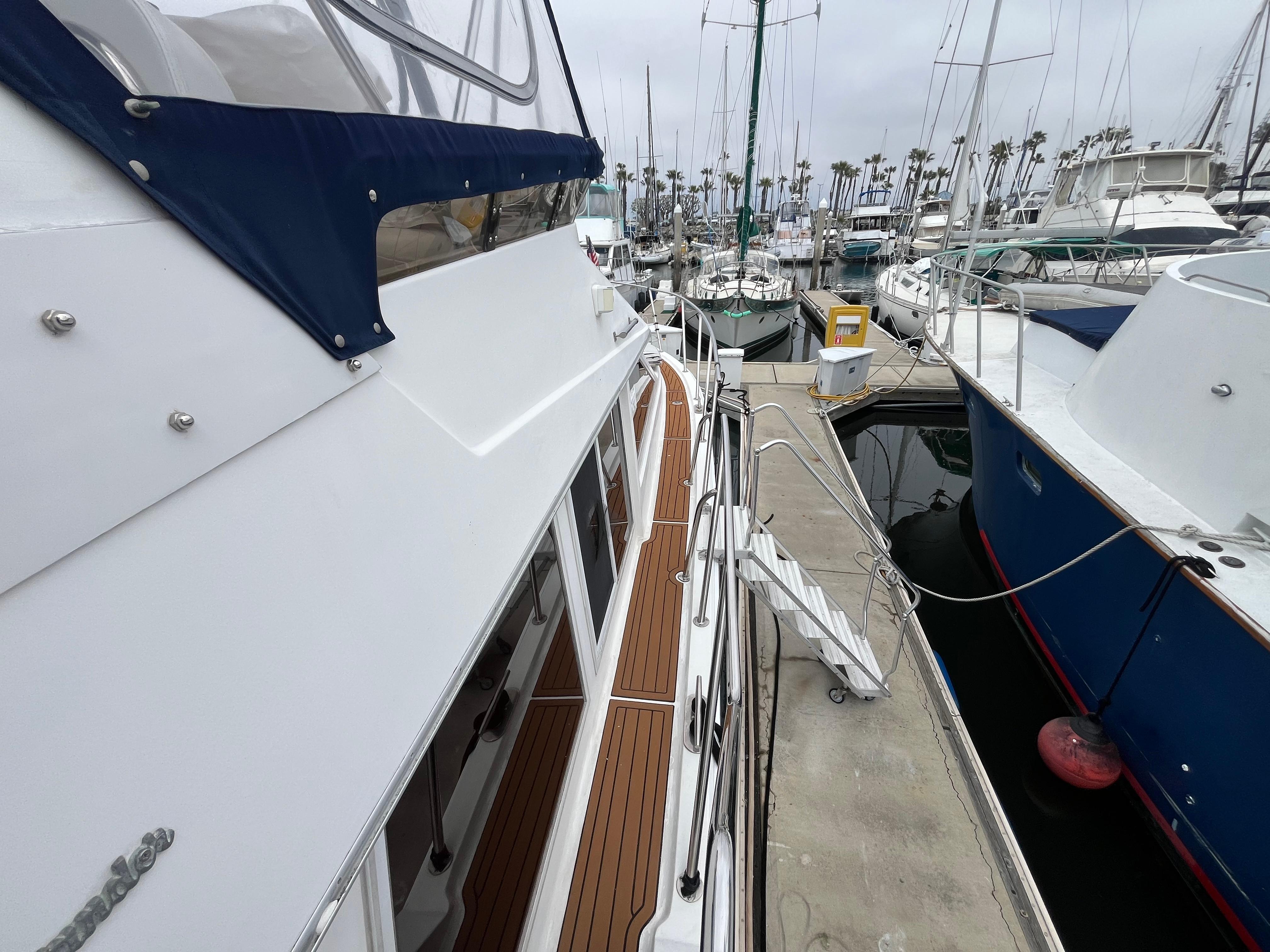 1999 Ocean Alexander Sundeck 460 yacht docked at marina, showcasing sleek design and wooden deck.