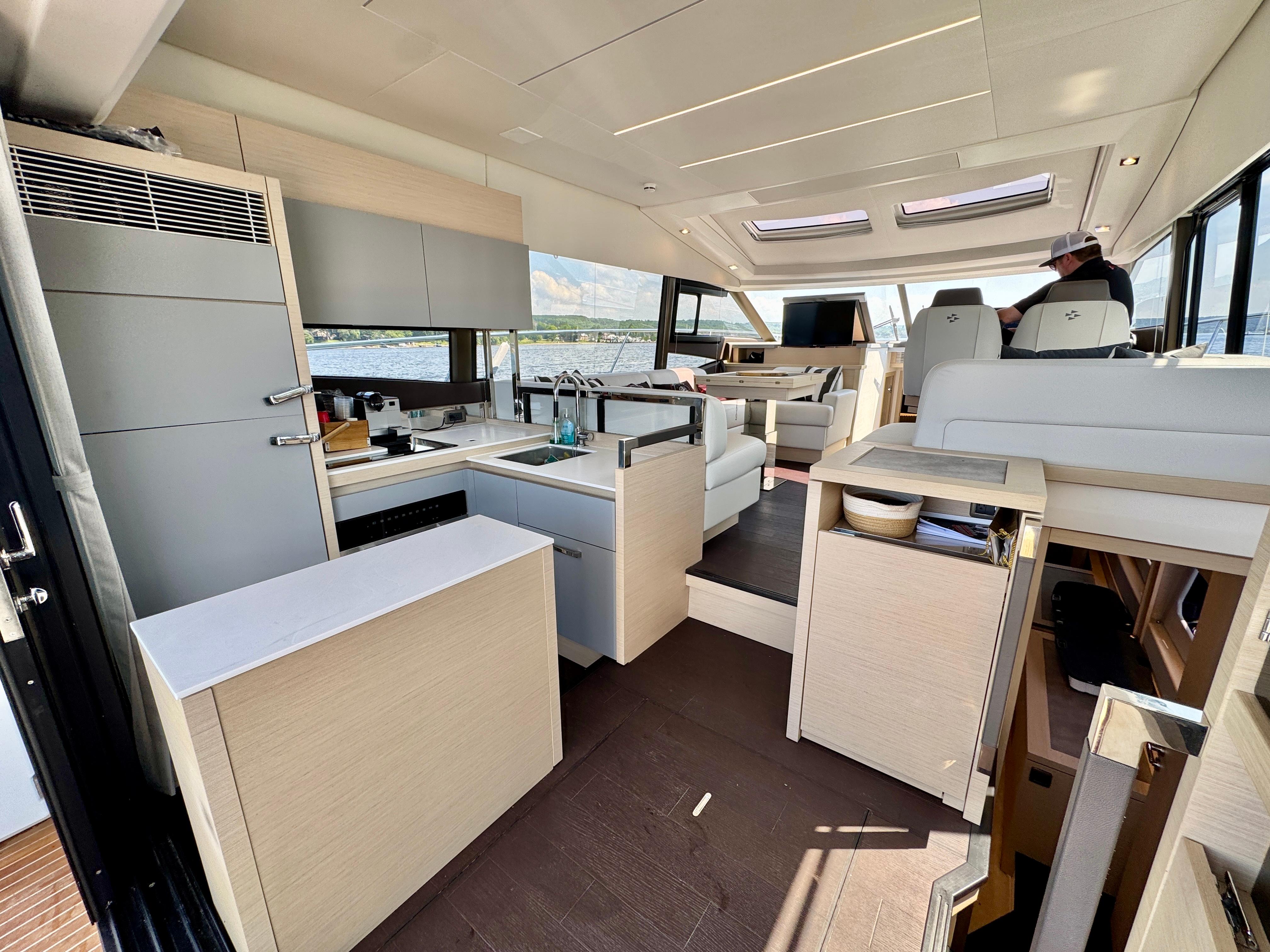 Luxurious interior of 2023 Prestige 520S yacht featuring modern kitchen and seating area.