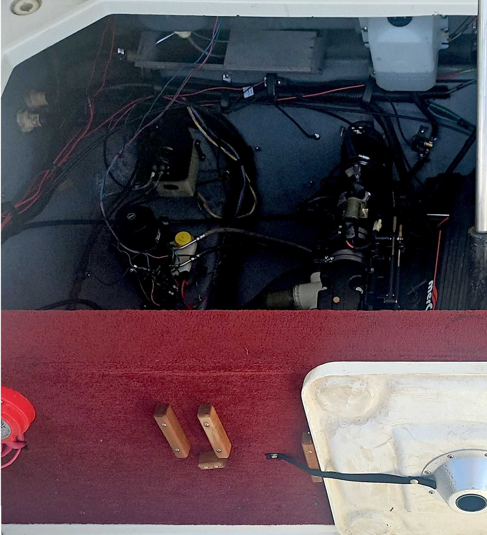 An open engine compartment of a boat with visible wires and components.