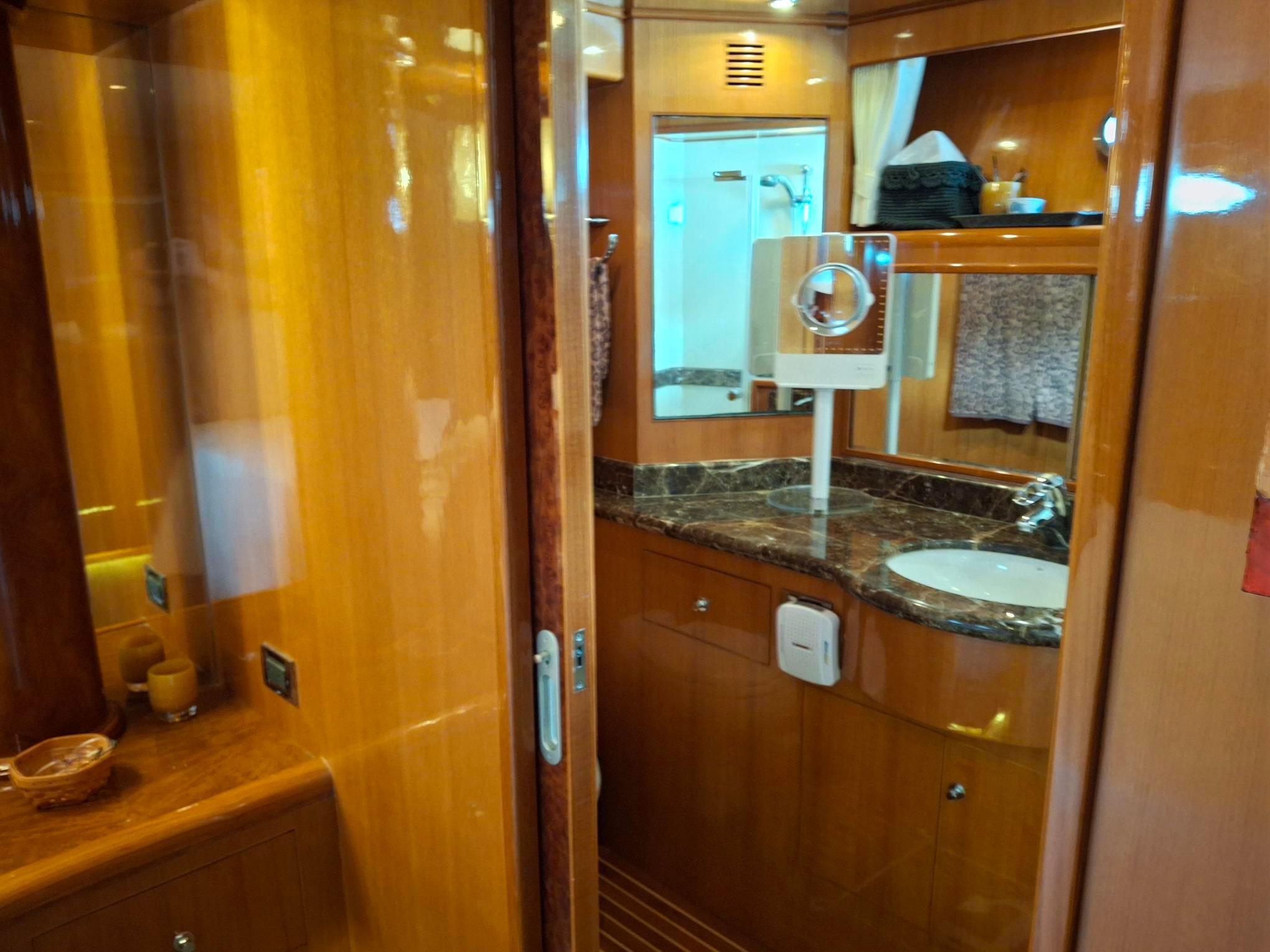Luxurious bathroom interior of 2004 Ocean Alexander 64 Pilothouse yacht with wood and marble finishes.