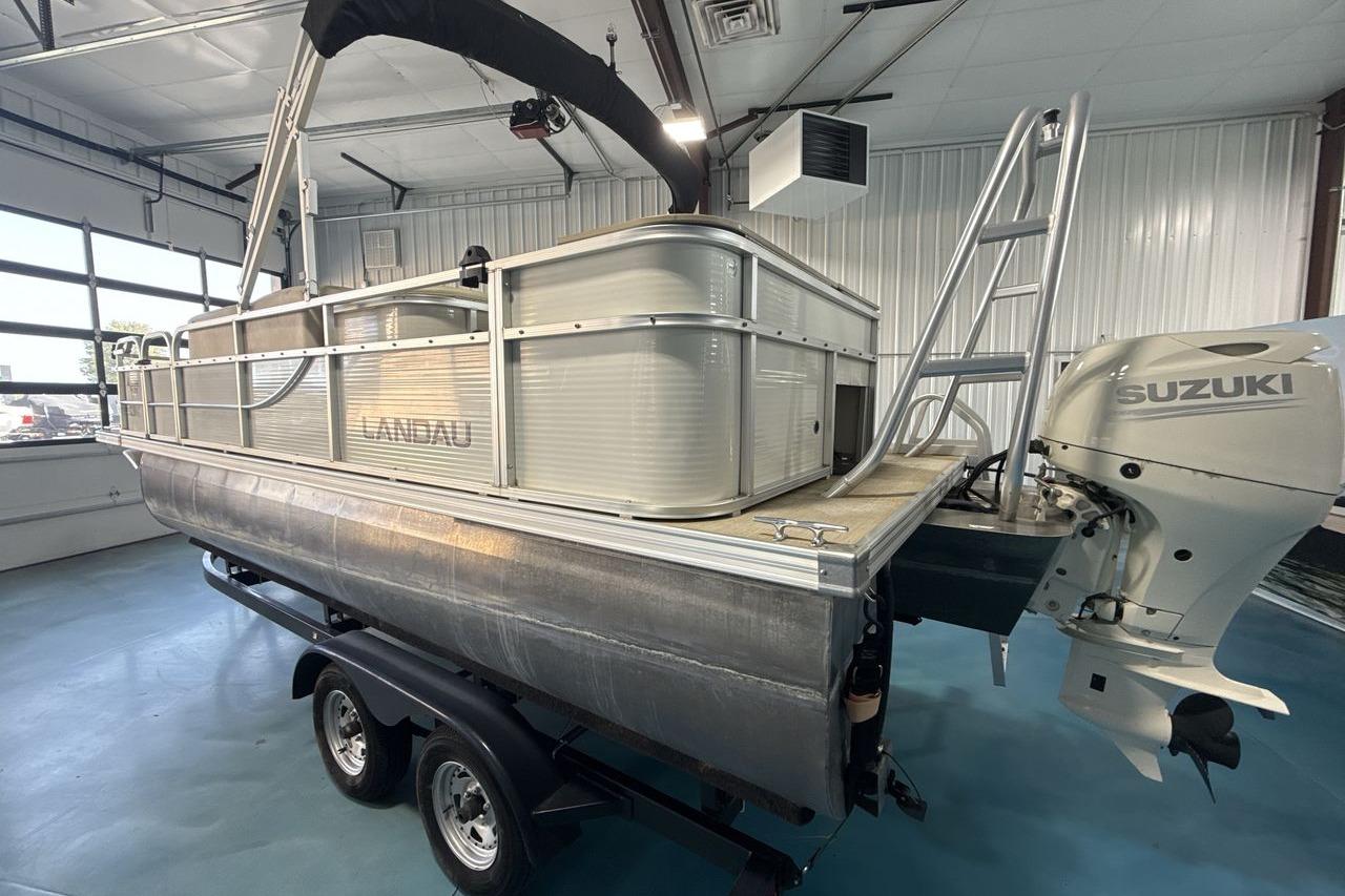 2018 Landau Alure 212 Fish pontoon boat with Suzuki outboard motor in a garage.