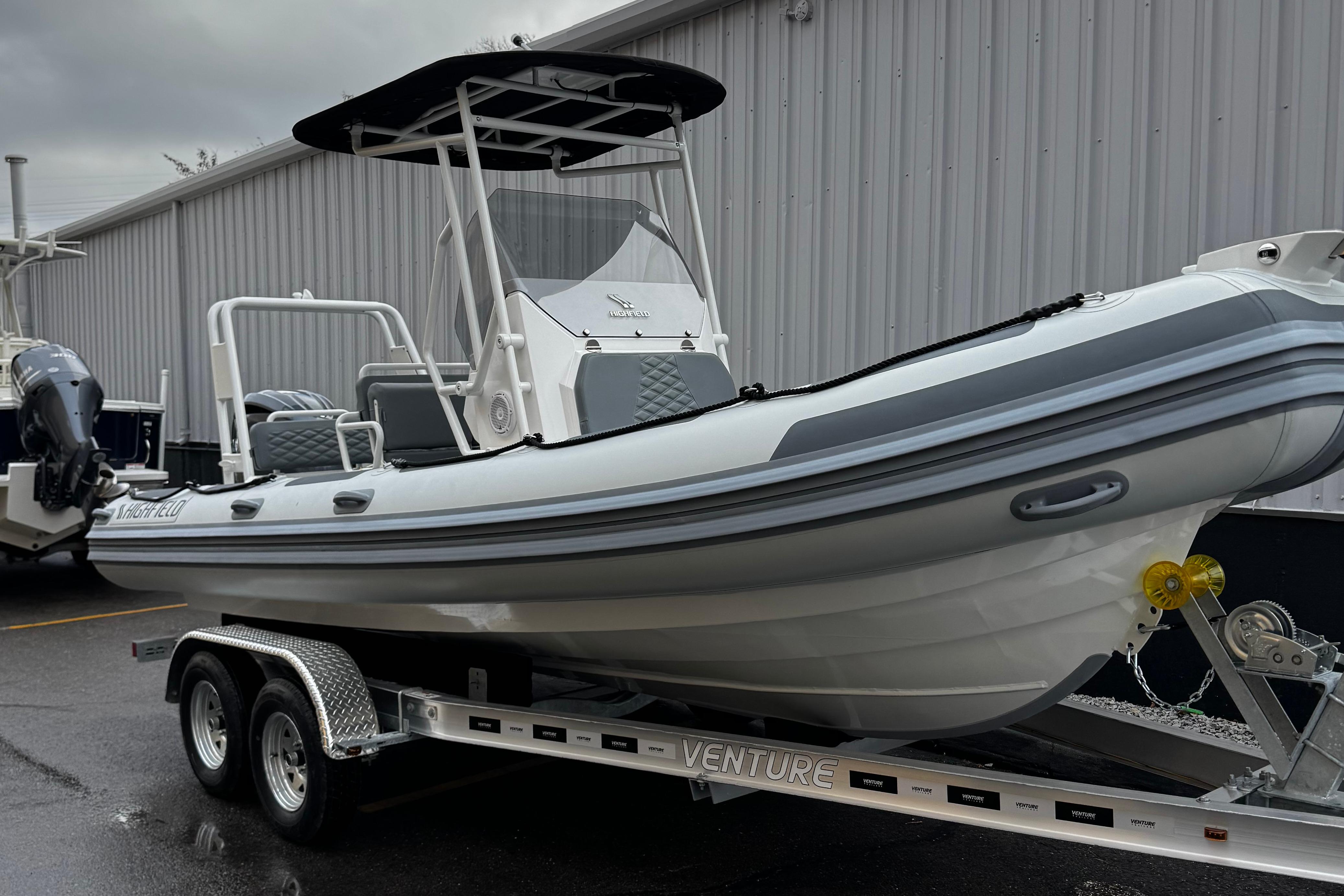 2026 Highfield Patrol 600 boat on trailer, parked outside a building.