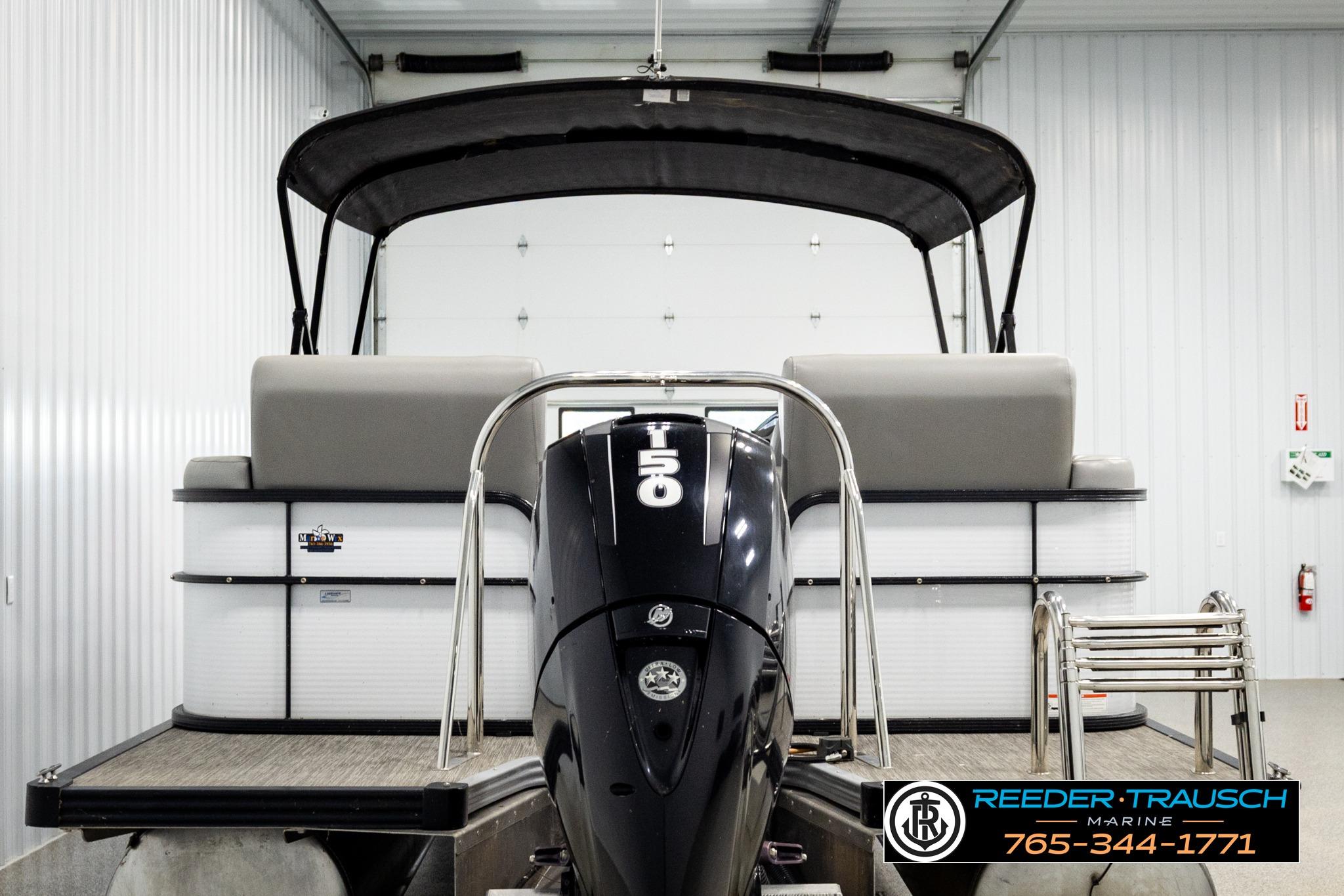 2019 Manitou Oasis SR VP pontoon boat with outboard motor in a storage facility.