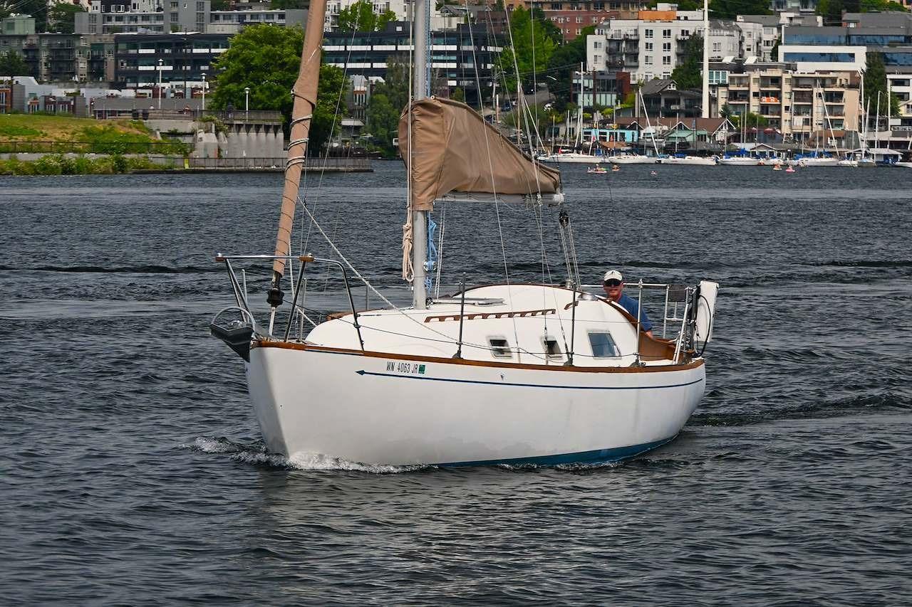 1977 Mercator Offshore sailboat cruising on a scenic urban waterway.
