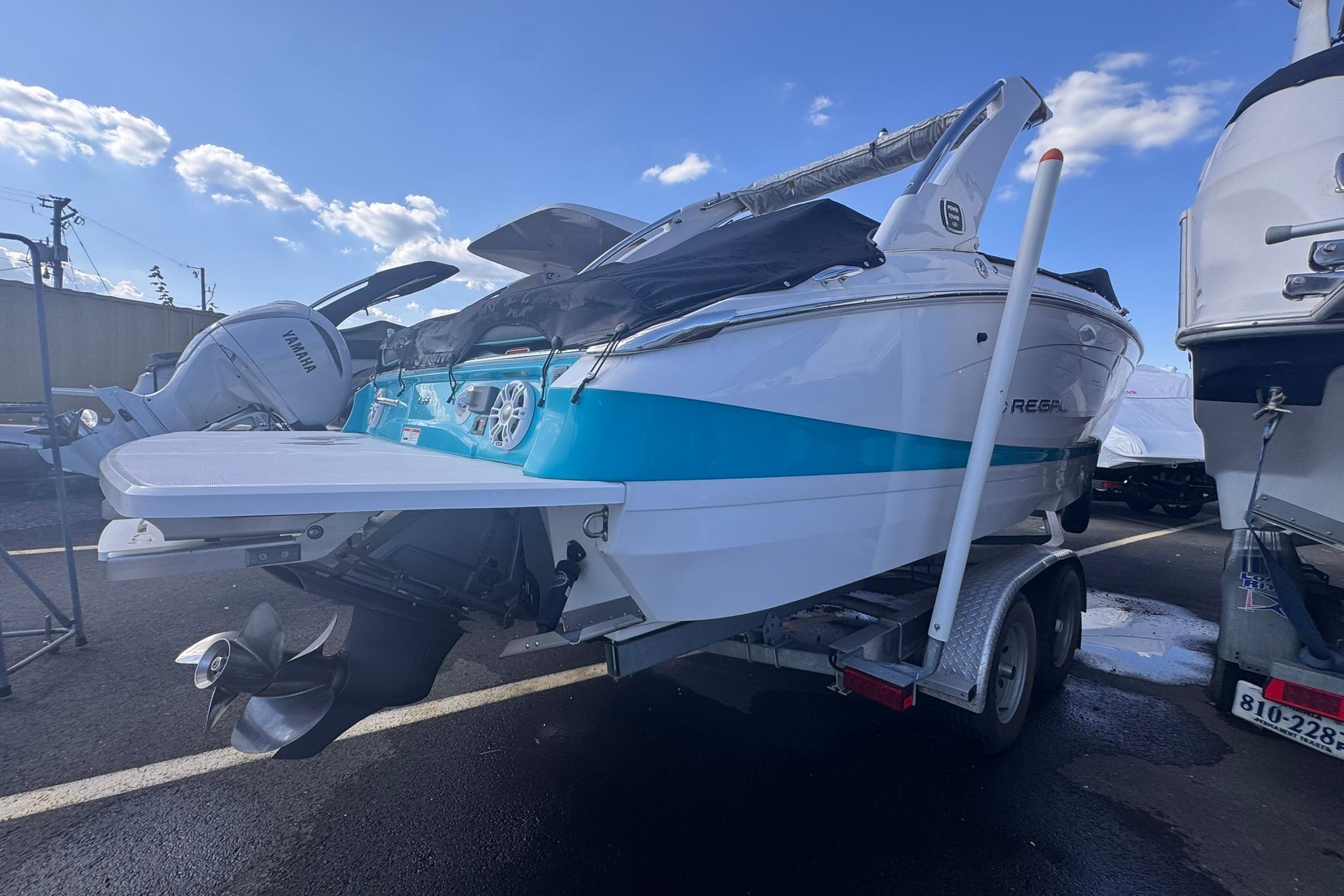 2020 Regal LS6 boat on trailer, blue and white design, parked outdoors.