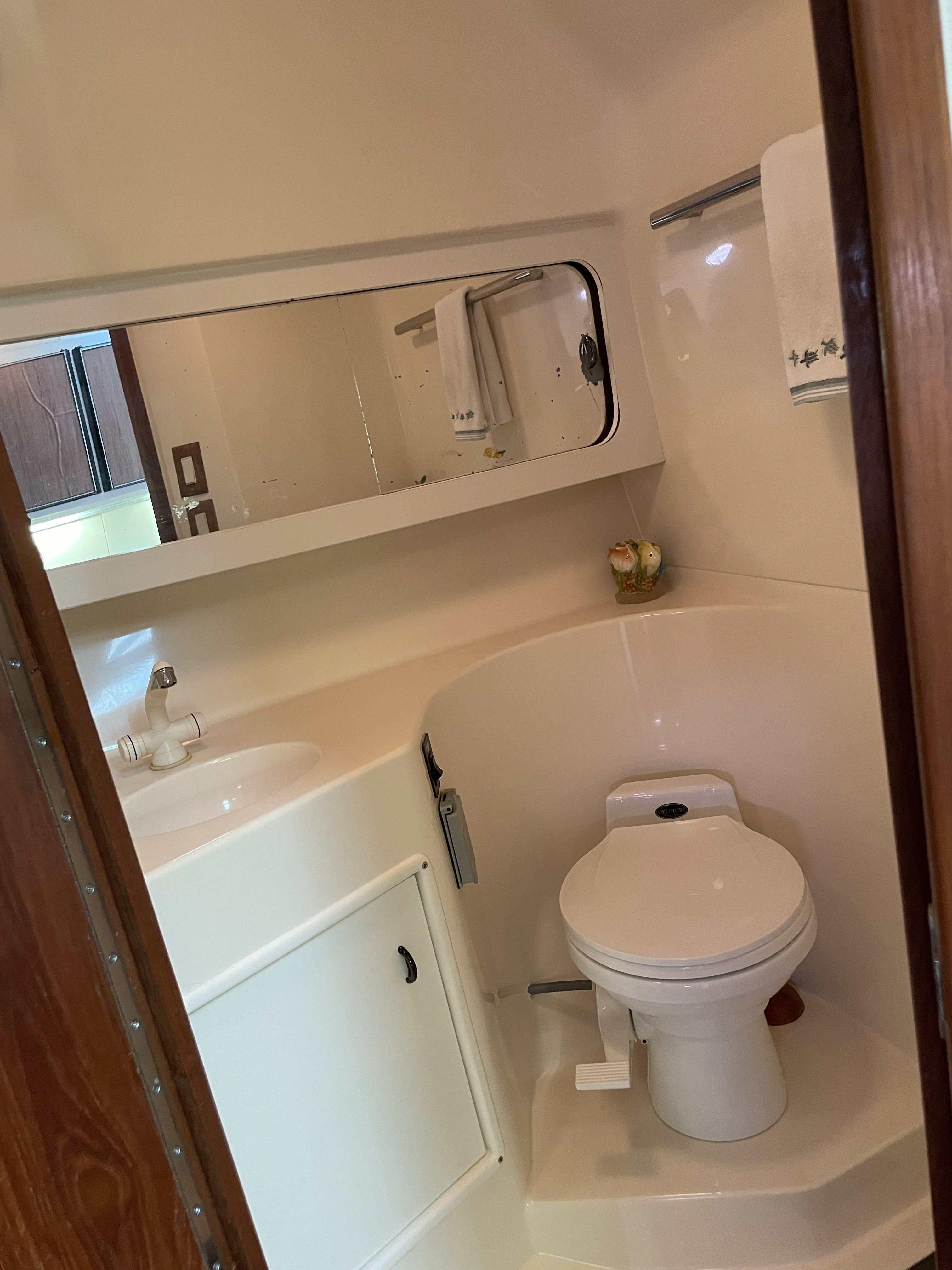 The image shows a boat bathroom with a toilet, sink, and mirror.