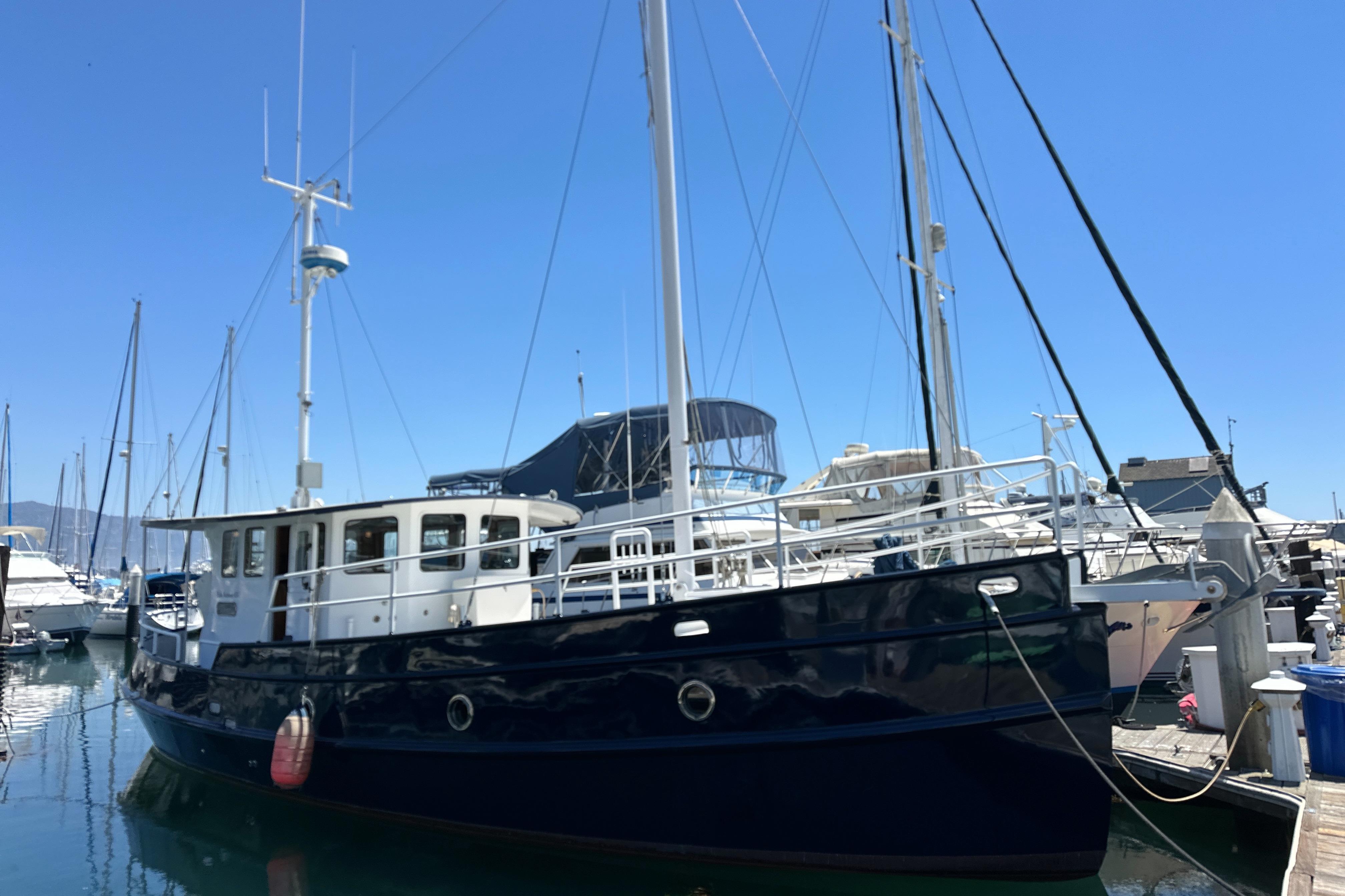 Custom Pacific Northwest 43 yacht, 2012 model, docked in a marina under clear blue skies.
