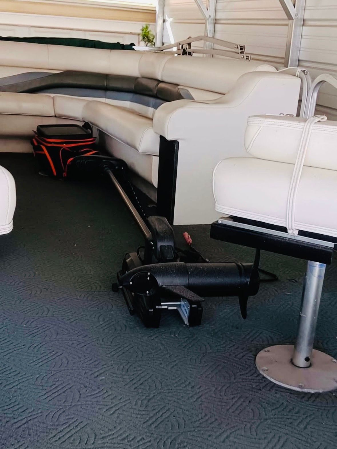 Interior of a boat with white leather seating and a black device on the floor.