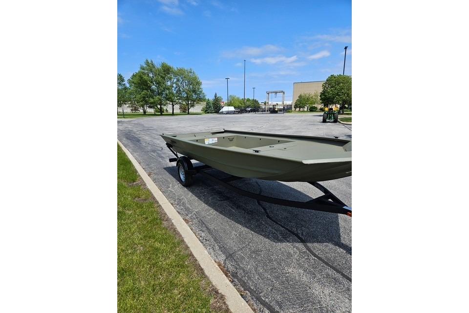 2026 Tracker Grizzly 1754 Utility boat on trailer in parking lot, under clear blue sky.